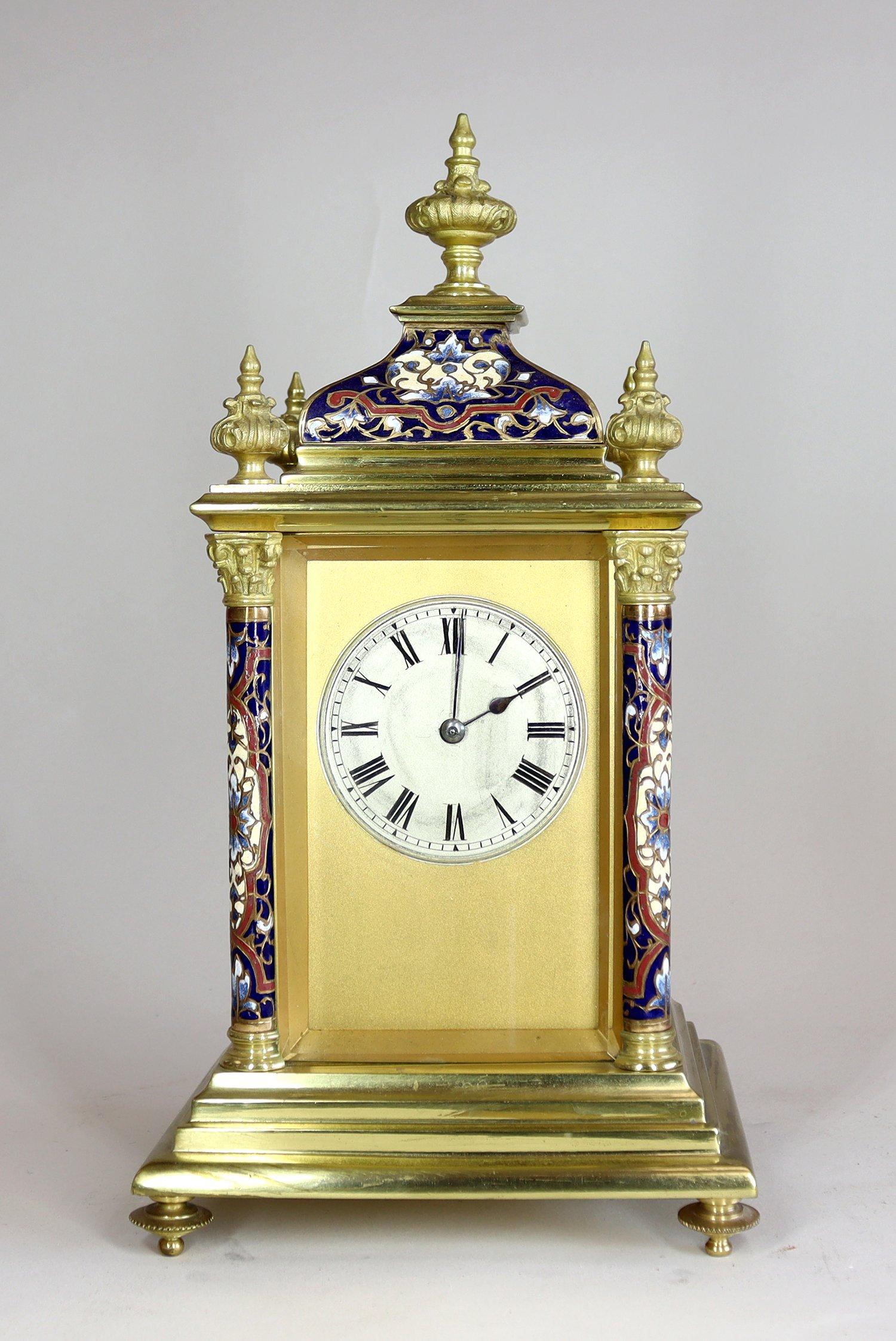 A charming enamel and brass mantel clock with champlevé enamel decoration, corinthian columns and foliate finials to the case. Housing an eight day movement, with original platform escapement striking on a gong. The silvered dial is framed by a