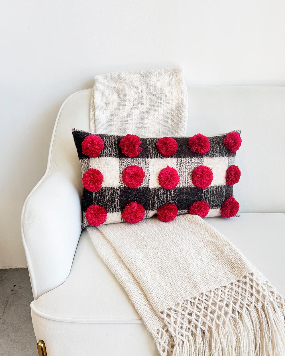 Add some subtle and elegant holiday vides to your home decor
This lumbar pillow from Chamula blends rustic charm with subtle holiday cheer. Crafted from wool, it features a black and white striped base with red pompom accents, ideal for seasonal