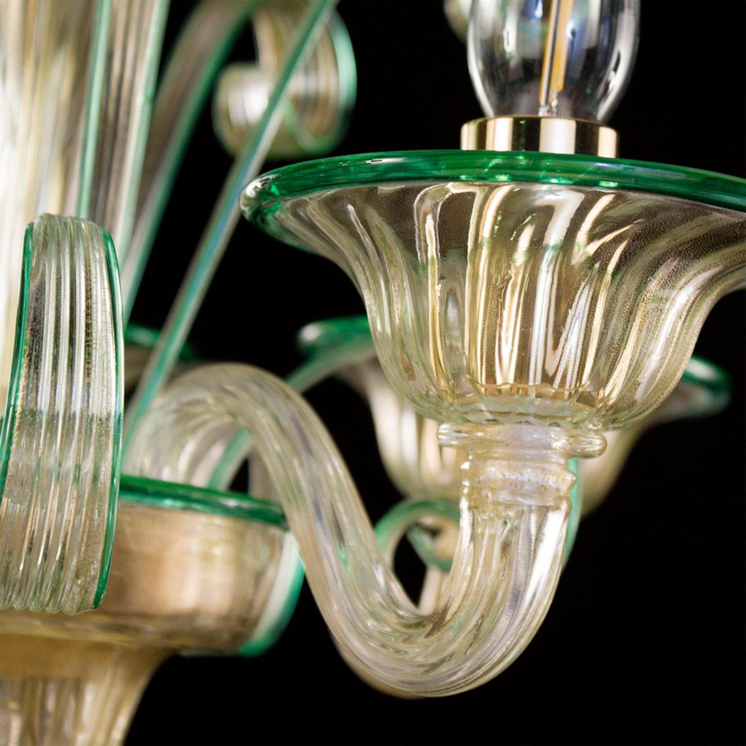 Lustre Capriccio, 5 lumières, verre artistique feuille d'or, avec des éléments ornementaux bouclés et des détails verts par Multiforme.
Inspiré de la tradition vénitienne classique, il se caractérise par une colonne centrale où sont installés de