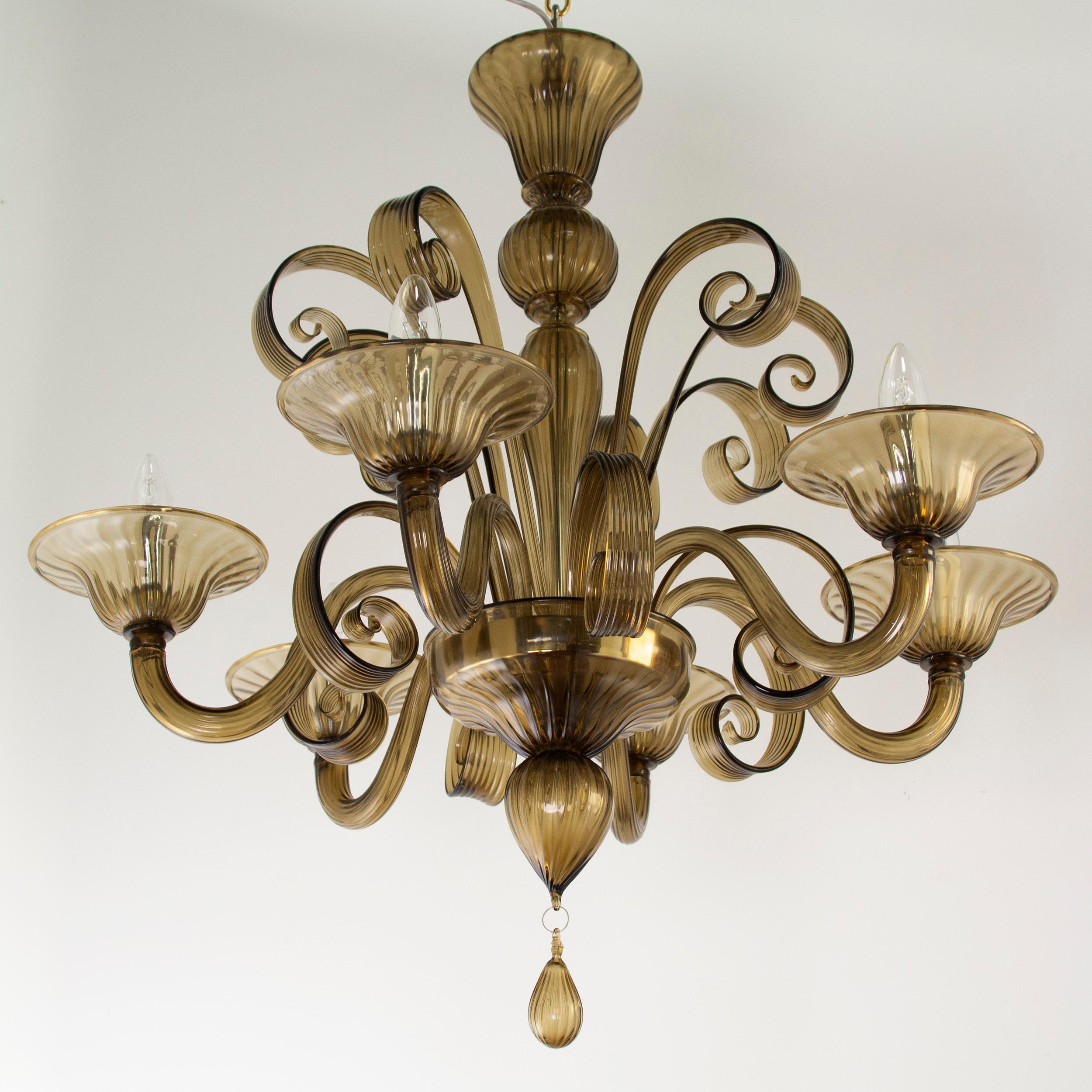 Capriccio by Multiforme is a 6 lights chandelier, in moka artistic glass, with curly ornamental elements.
Inspired by the Classic Venetian tradition it is characterized by a central column where many blown glass “pastoral” elements are installed.