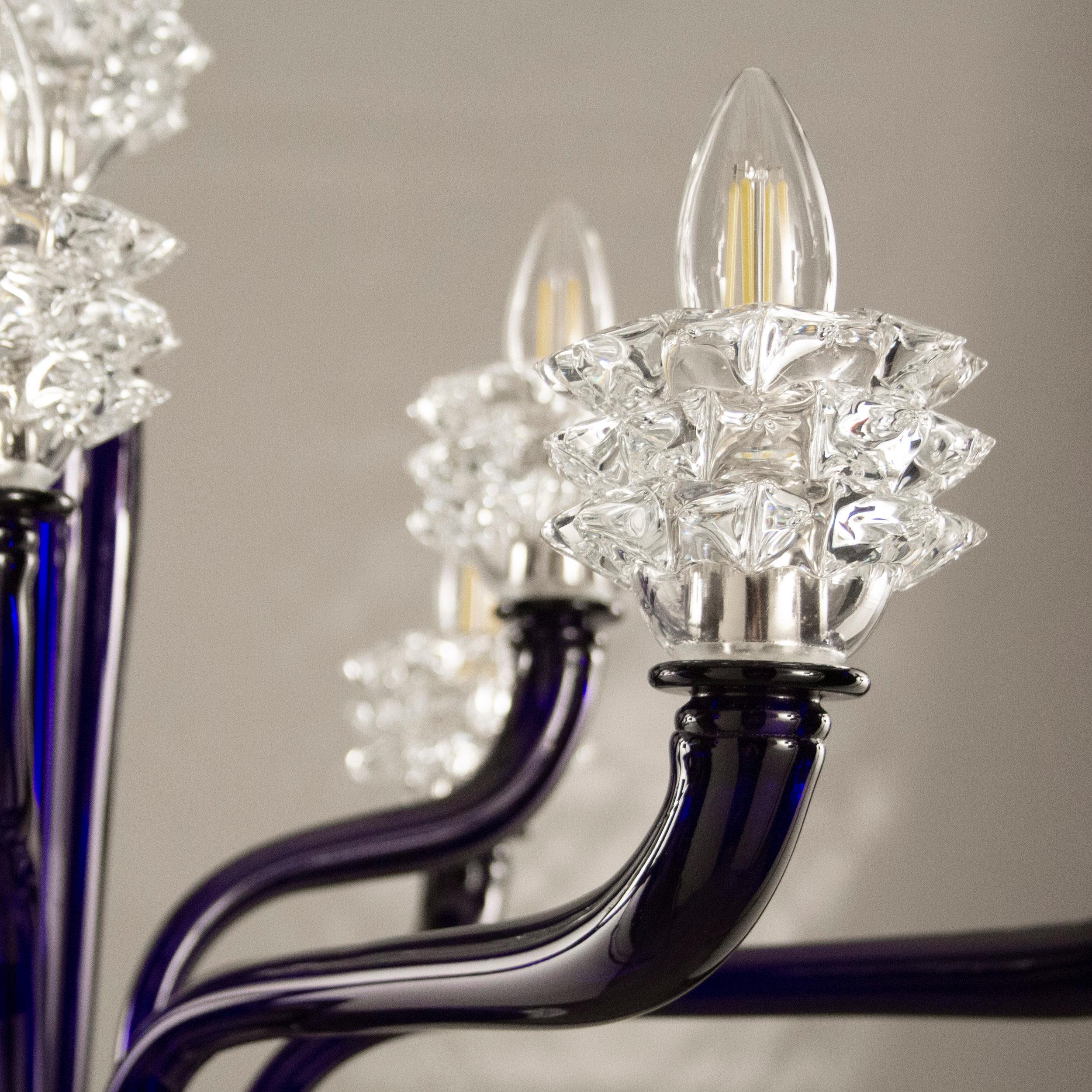 The diamante blown glass chandeliers are characterized by a slender central element.
The arms, central column and final cup are made of flawless smooth glass. The standout elements of this chandelier are the cups, which are created using a complex