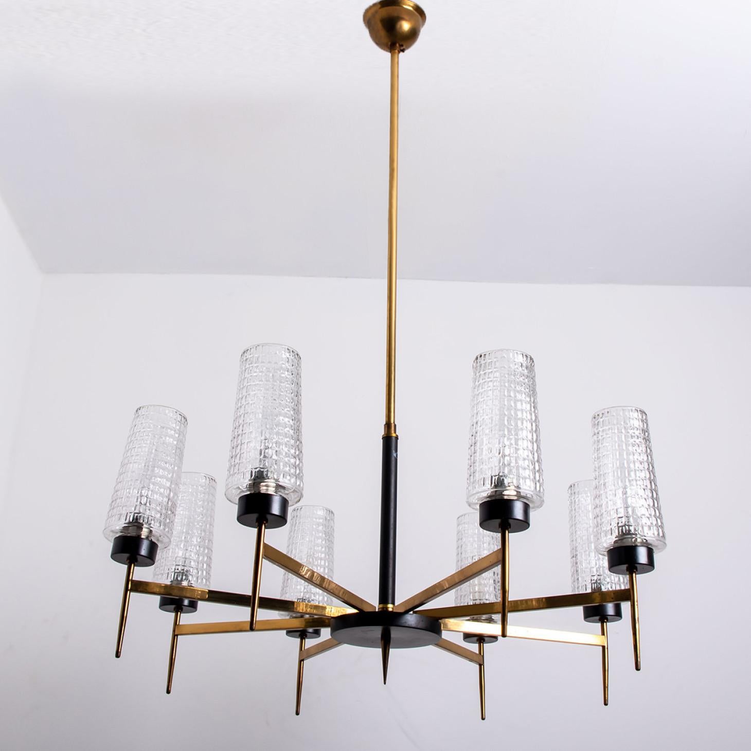 Modernist example of traditional elegance. Quality brass frame in an elegant warm gold color, consisting of eight arms gathering in the middle of the fixture forming a sun pattern.

The 8 waffle pattern glas shades are mounted on a brass and black