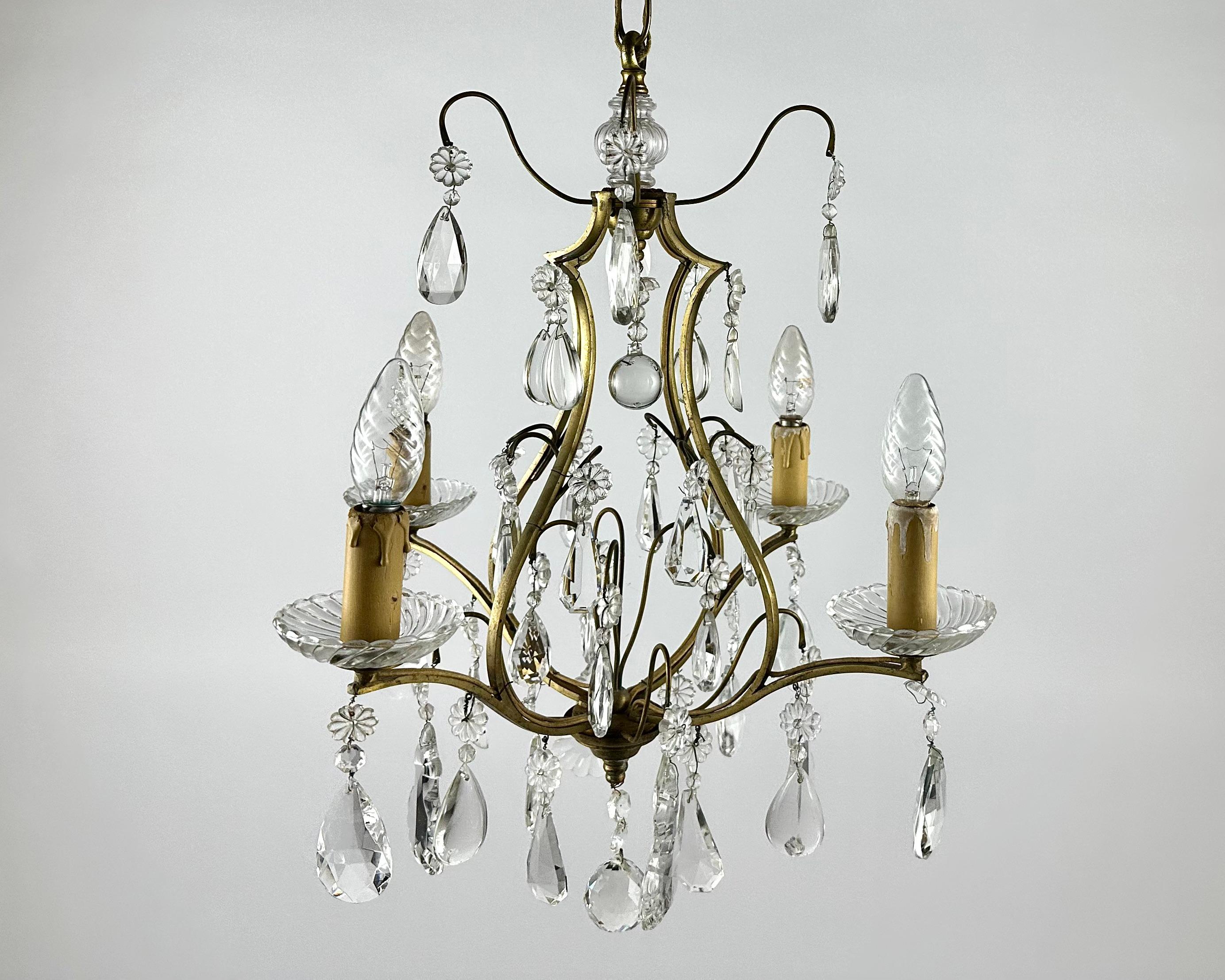 Gilt bronze chandelier with four arms of light holding crystal pendants.

Circa 1910-1920s Baroque Style Chandelier with four light bulbs.  

Manufactured in France.  

Richly fecorated chandelier's framework is in gilt brass with transparent cut