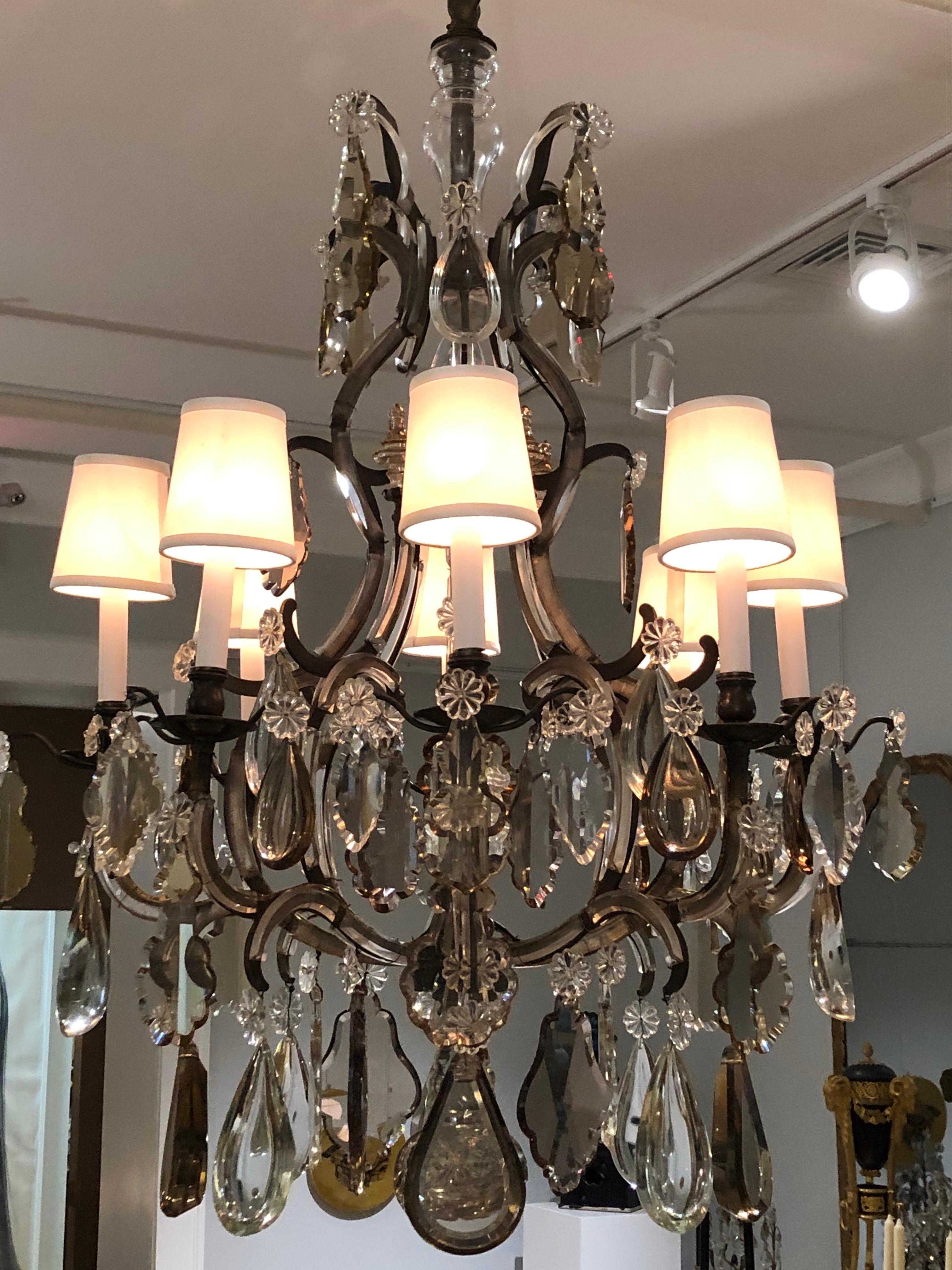 Questo lampadario francese degli anni '30 adatta una forma dell'Ancien Regime al gusto della Cafe Society. I bracci sono3 rifiniti con arabeschi di vetro tagliato, la cornice è in acciaio anziché in ormolu, ed è festonata da prismi tagliati da