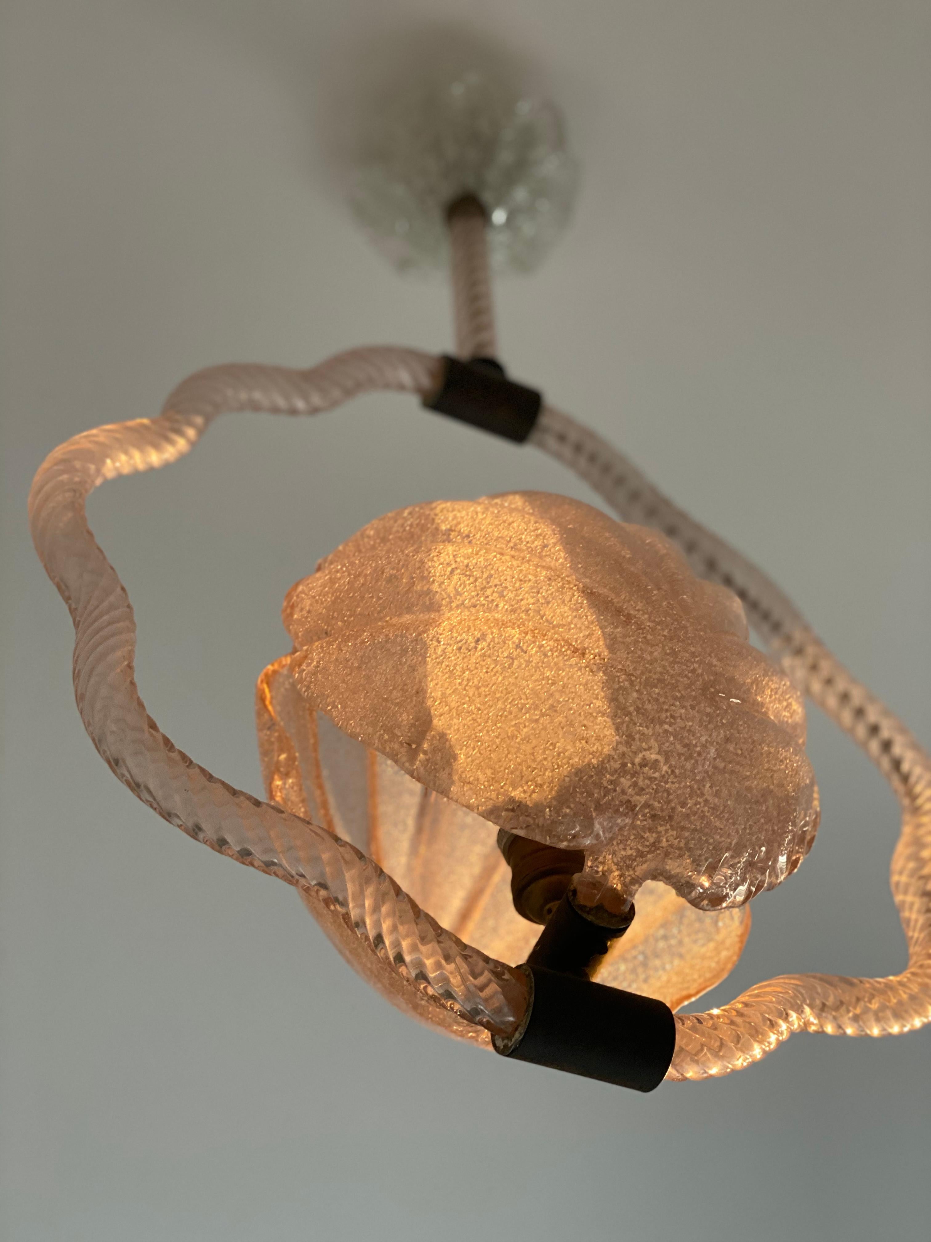 The Vintage Chandelier by Barovier & Toso showcases a central cup in seashell form with rare pink glass, bringing coastal beauty and natural elegance to the space, evoking the soothing qualities of the ocean.
The captivating design includes a