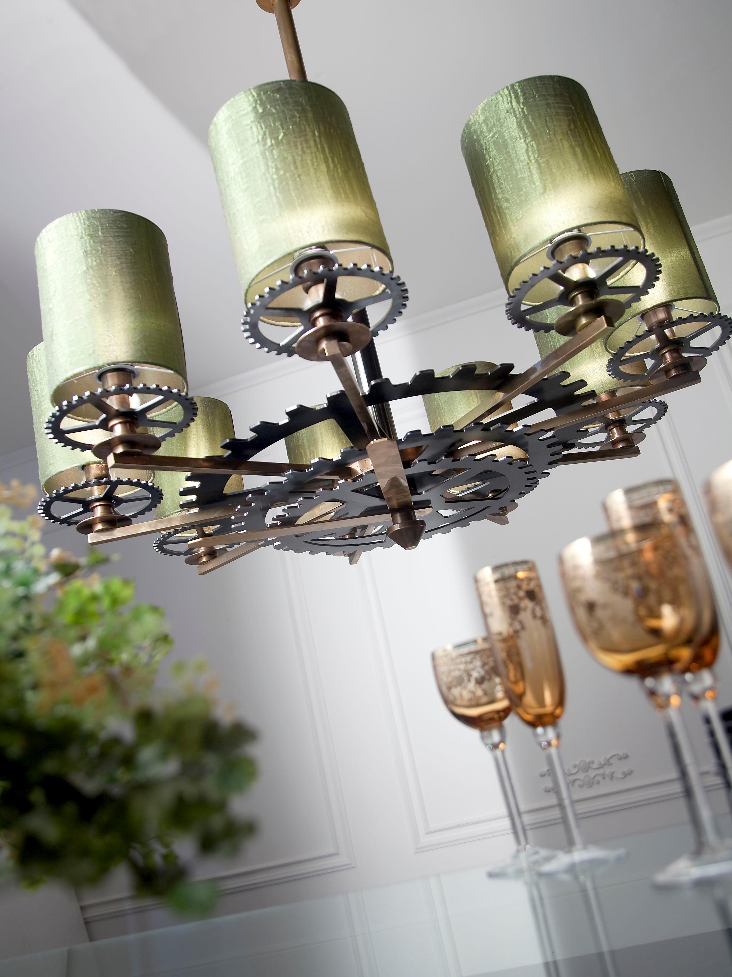 Chandelier in brass in burnished bronze finish. The iron gear wheels are in pewter finish. Lampshades in silk green.
 