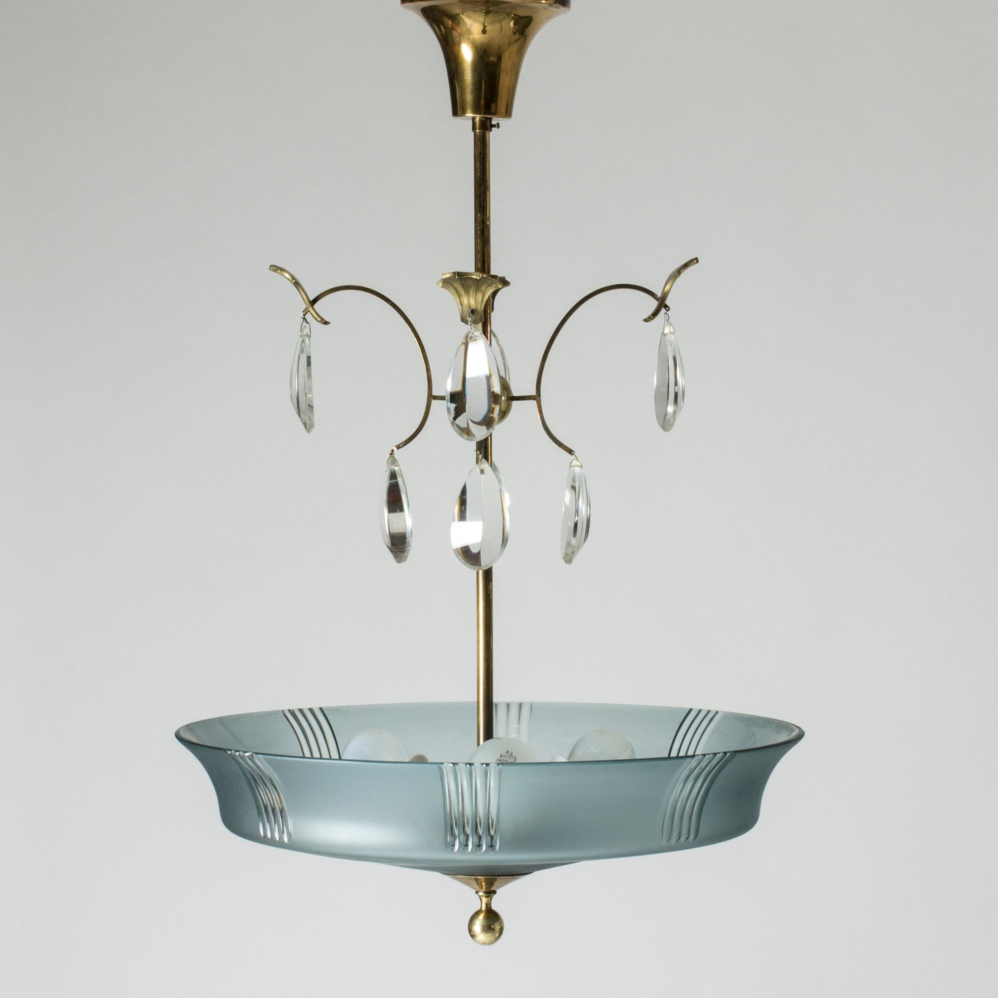 Beautiful chandelier by Elis Bergh, made from blue tinted, frosted glass. Graceful design with drop-shaped crystal glass prisms and decorative brass details.
