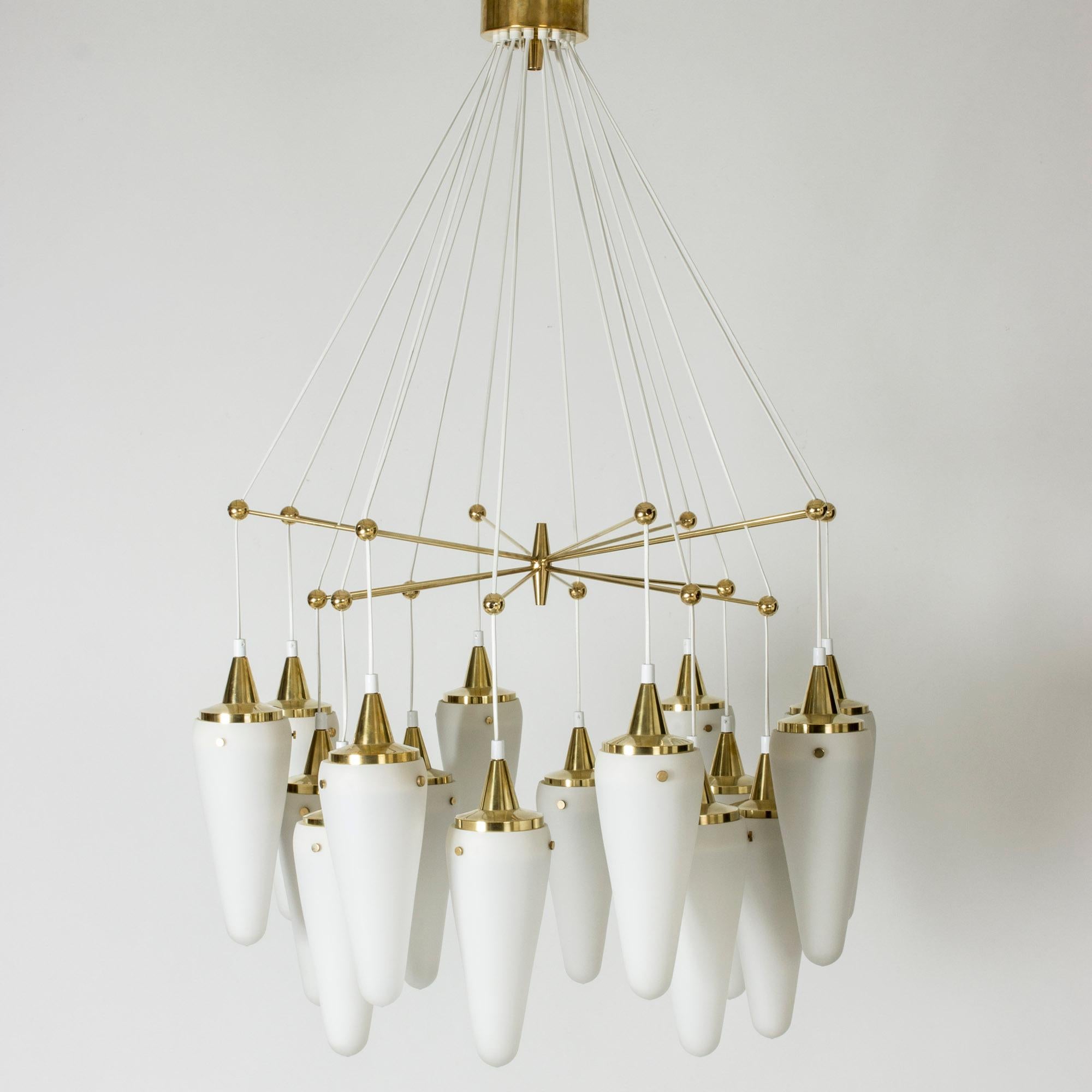 Stunning chandelier by Hans-Agne Jakobsson, in a rare, luxurious design. Beautiful brass frame with arms coming out from the center, with balls at the ends, suspending sixteen opaline shades.
