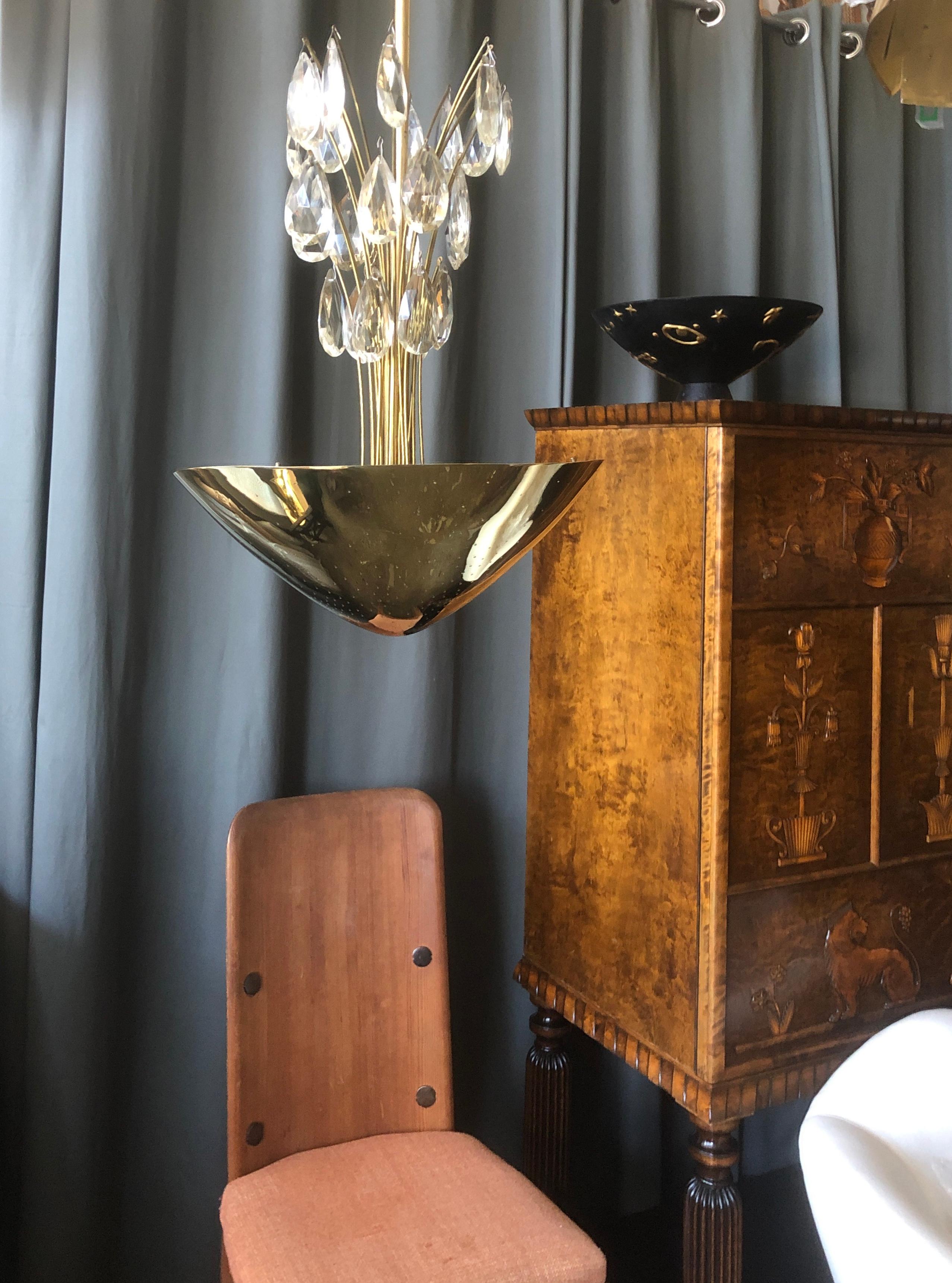 Un lustre conçu par Lisa Johansson-Pape pour Orno, Finlande, Circa 1950th.
Abat-jour en laiton perforé poli et pampilles en cristal sur des poteaux en laiton.
3 douilles de style Edison. 
Câblage existant, recâblage disponible sur demande.
Articles