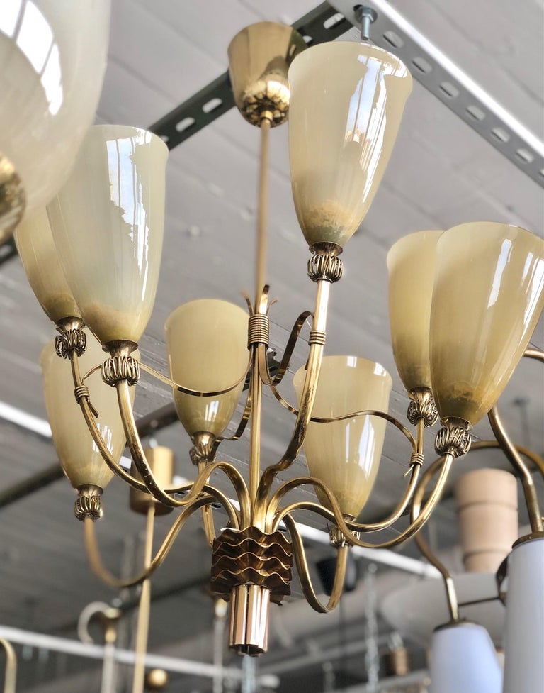 A brass chandelier with eight glass shades, designed by Paavo Tynell for IDMAN ,  Finland, Circa 1950th.
Similar model featured at IDMAN catalog #136, page 14.
Rewiring available upon request.