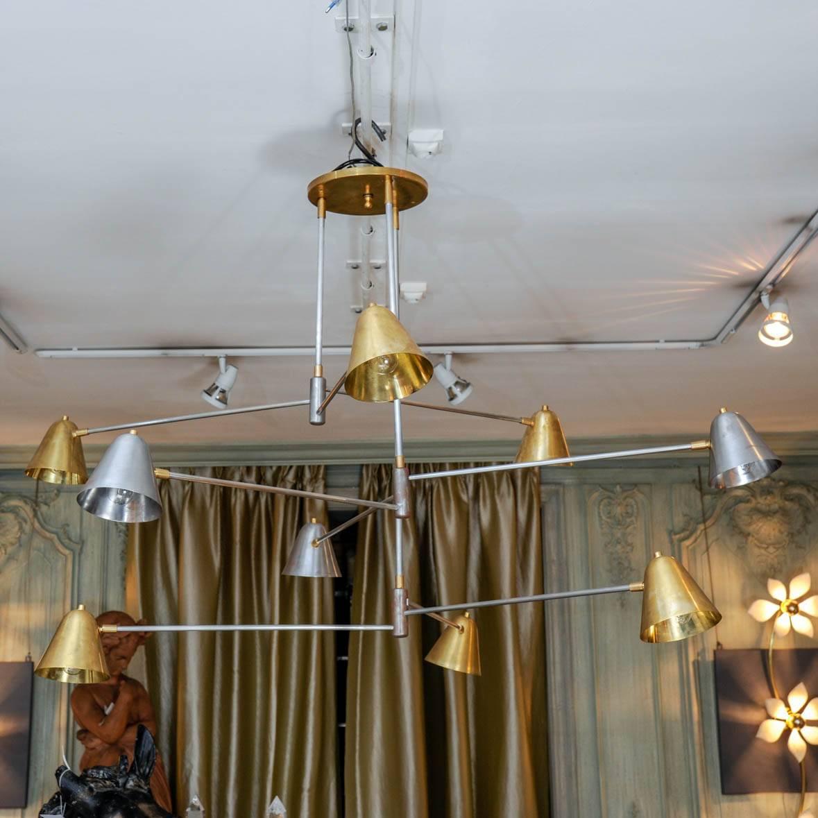 This chandelier is a creation of the Studio Glustin. It is made of brass and steel, and composed by nine lights with rotative metal lampshades.