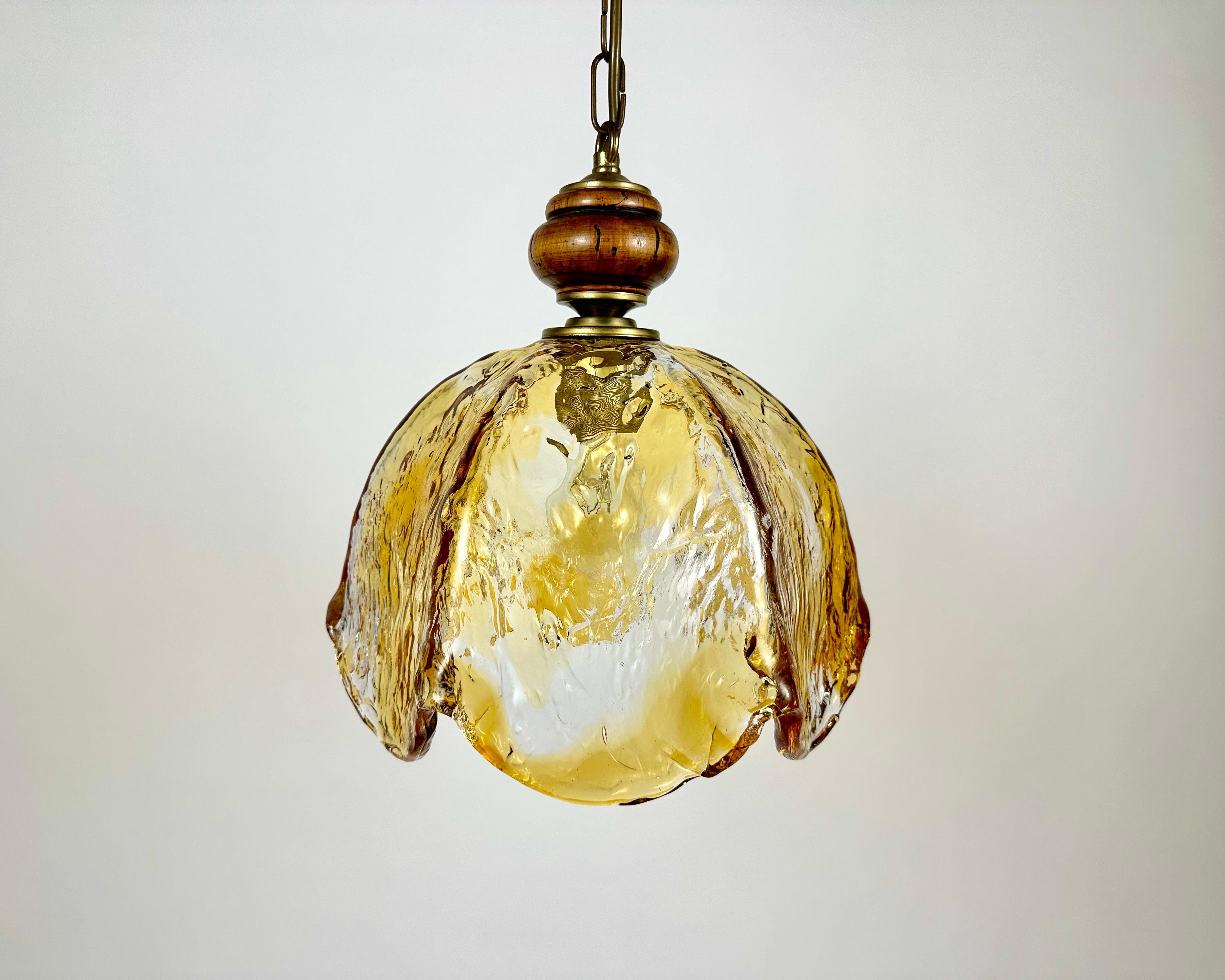 Thick Murano glass chandelier designed by Carlo Nason for Mazzega in the 1970s.

The glass shade is made from textured clear glass with an amber tint.

The chain and the rosette are made of brass.

The spectacular blown shape of the lampshades and