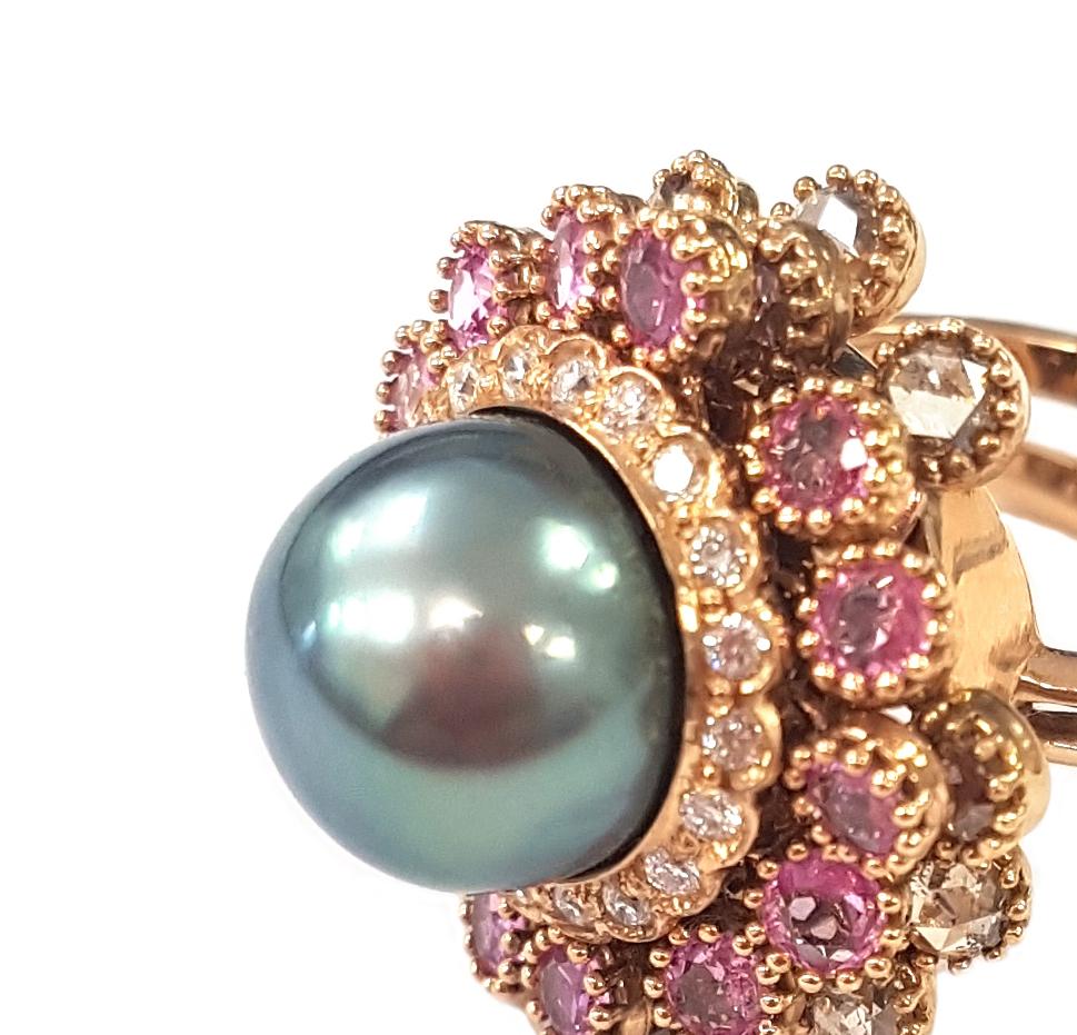 Masterfully created entirely by hand, a sparkling 2.96 carats of pink sapphires and 1.59 carats of diamonds and a large 9.8-carat grey Tahitian pearl feature on this whimsical cocktail ring. The pearl is set atop a halo of round-cut white diamonds