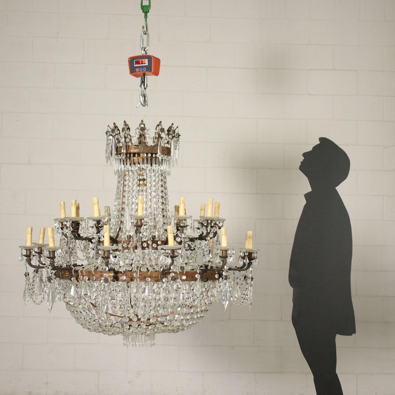 Empire style balloon shaped chandelier, two tiers, twelve lights. In bronze decorated with Empire-style ornamental motifs, it is adorned with glass necklaces and pendants.