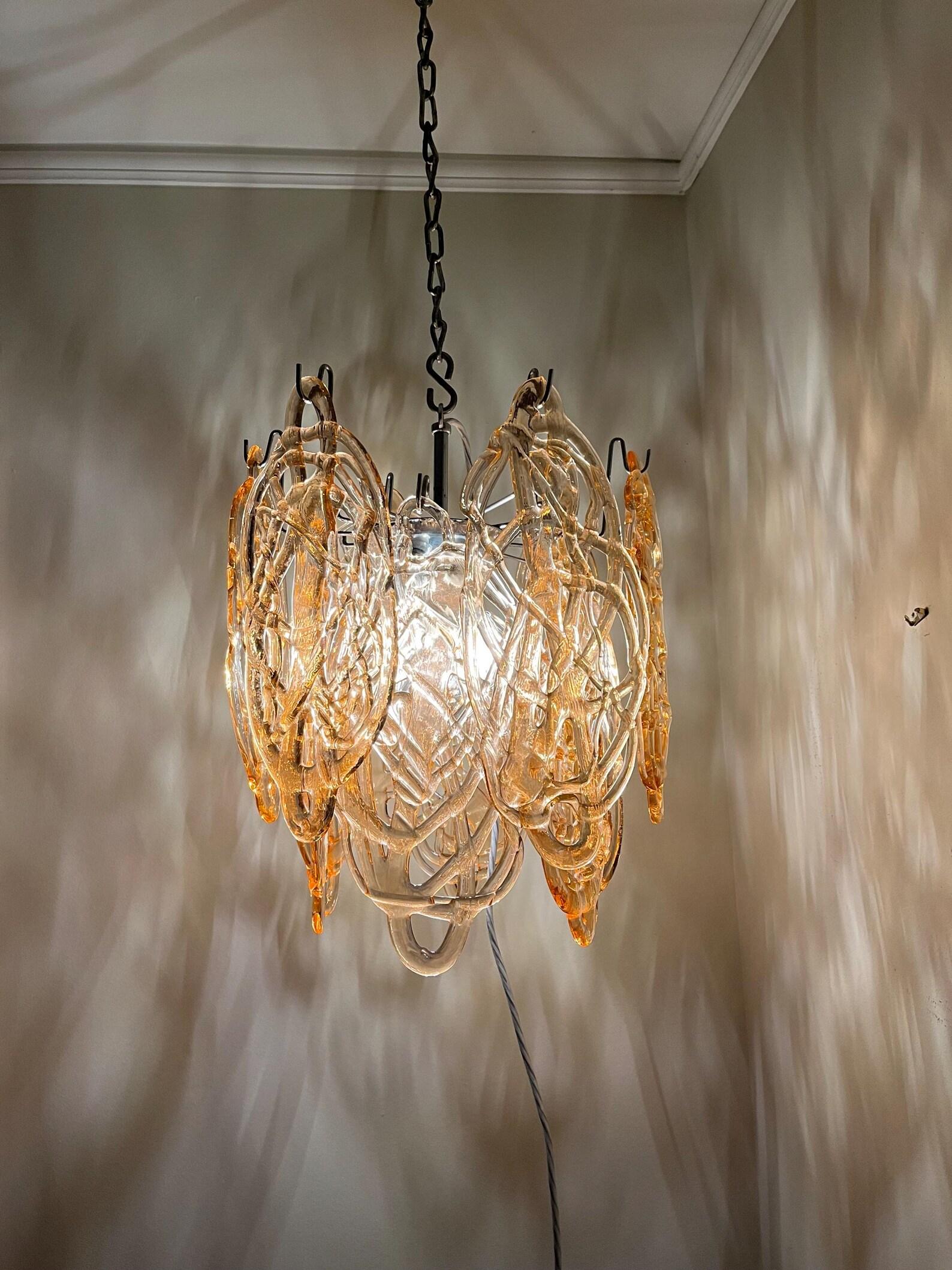Lampadario in vetro soffiato a bocca. Di metà secolo, proveniente da Murano, Italia. È straordinariamente bello grazie alle sfumature di colore oro ambrato e al design in vetro intrecciato. 

Un centrotavola sospeso sul tavolo da pranzo. O forse
