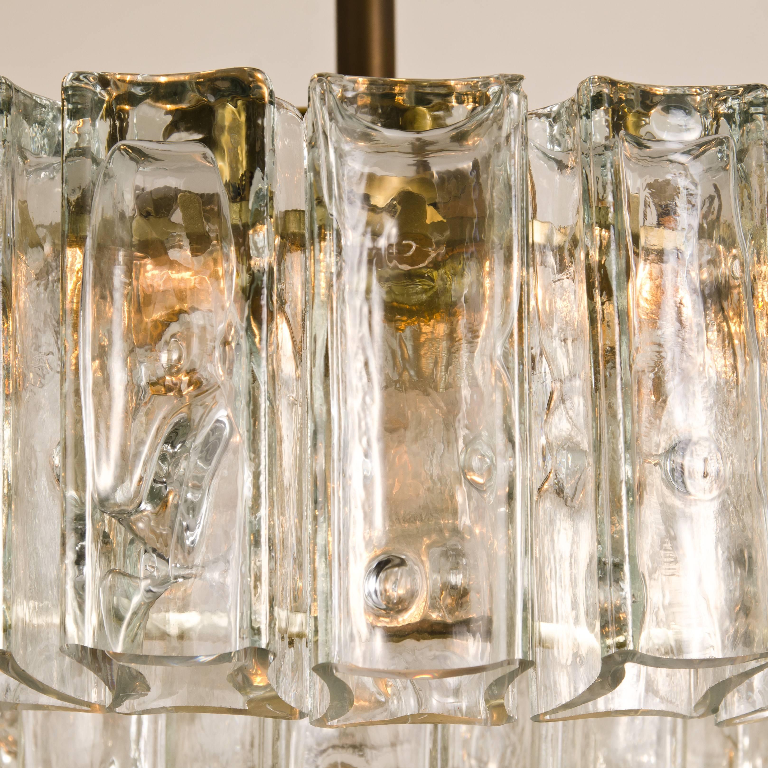 Wonderful and very heavy quality chandelier made by Kalmar, Austria, manufactured, circa 1970-1979. The chandelier has four sockets and two layers of extremely stylish solid glass tubes dangling on it. The sheets beautifully refracting light. It
