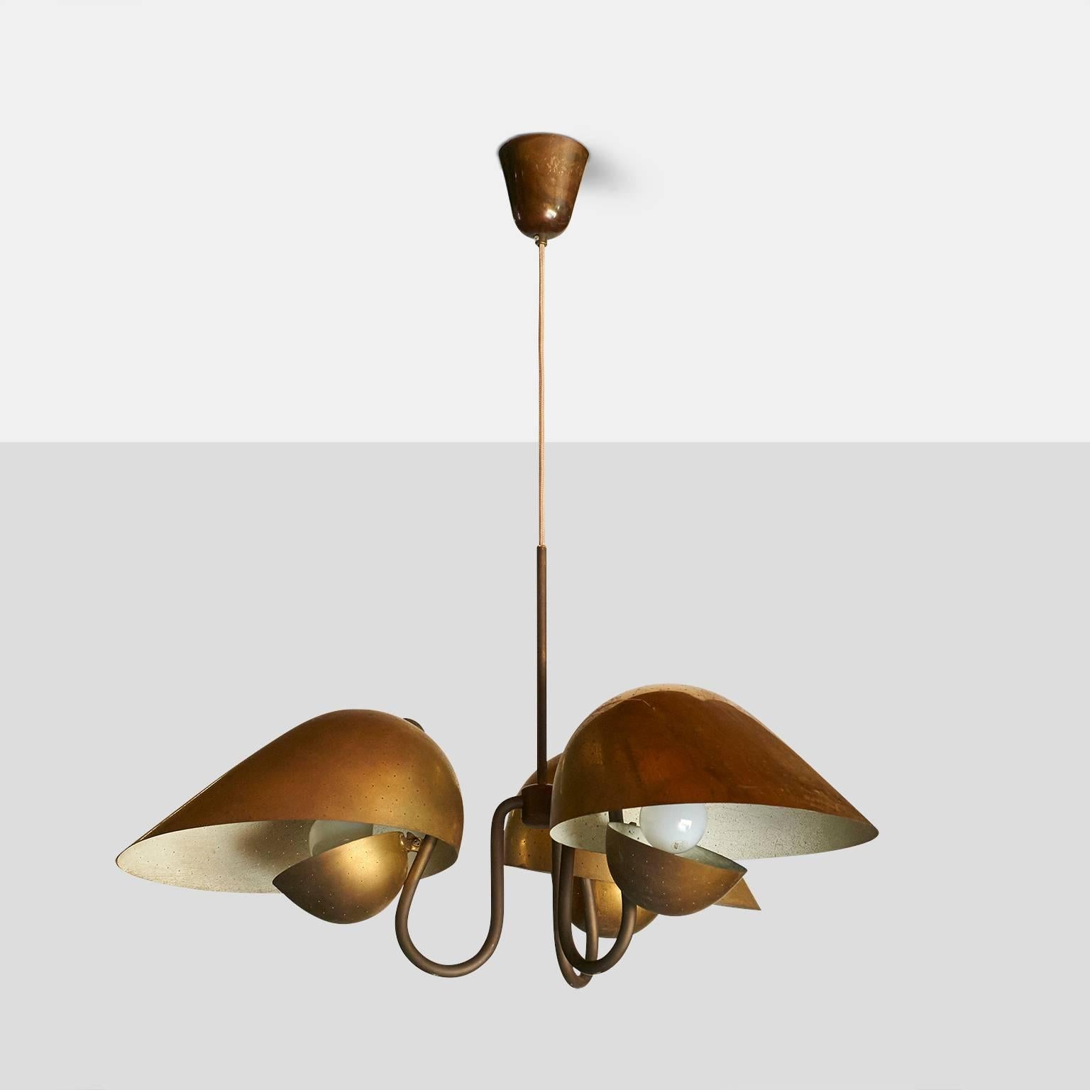 A 1940s chandelier in natural patinated brass, by Carl-Axel Acking for Bro¨derna Malmstro¨ms Metallvarufabrik. Each S-curved arm holds a curved shade with pinholes and a smaller diffuser underneath. Can be adjusted to any overall length