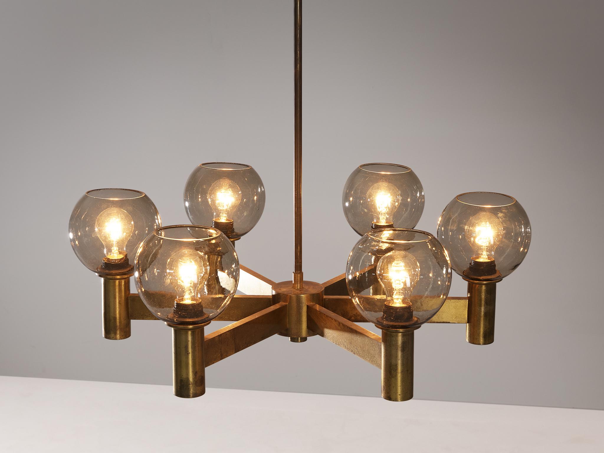 Chandelier, glass, brass, Sweden, 1960s. 

The patinated brass chandelier is designed with six arms, each elegantly paired with a glass bulb. The spatial arrangement of the shades allows for an even distribution of light throughout the room. The