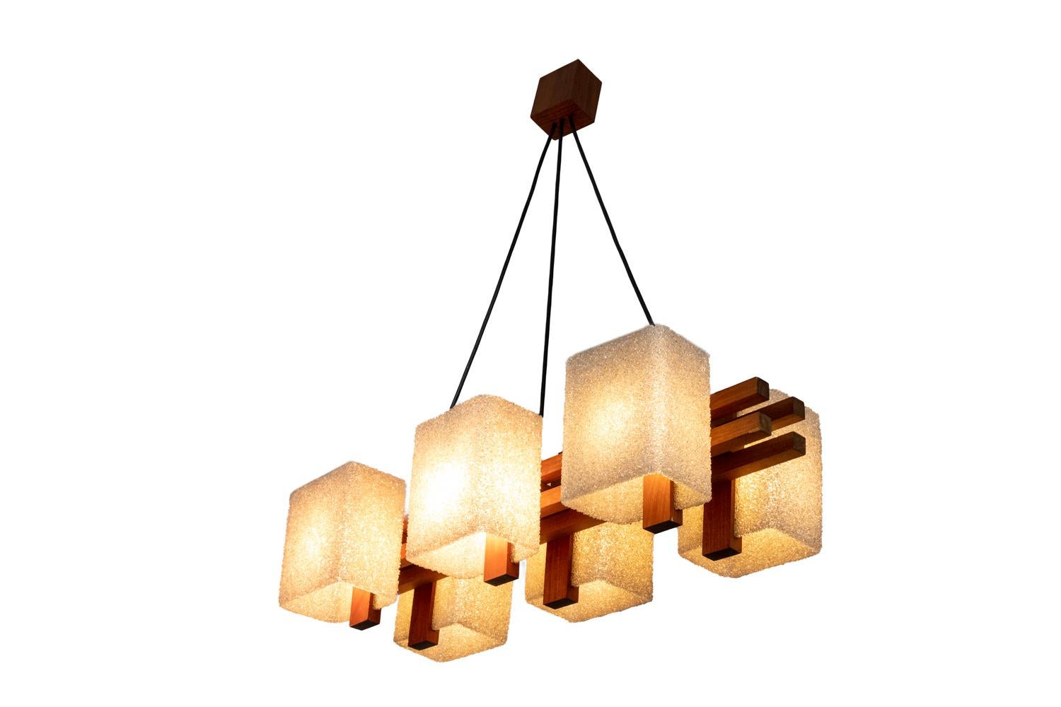 Chandelier in granite resin and wood with six lights. Wood shaft composed by four rectangular shape sticks on which are hung six rectangular shape lampshades. Black wires hung on a wood cylindrical cache-bélière (hide hook).

Work realized in the