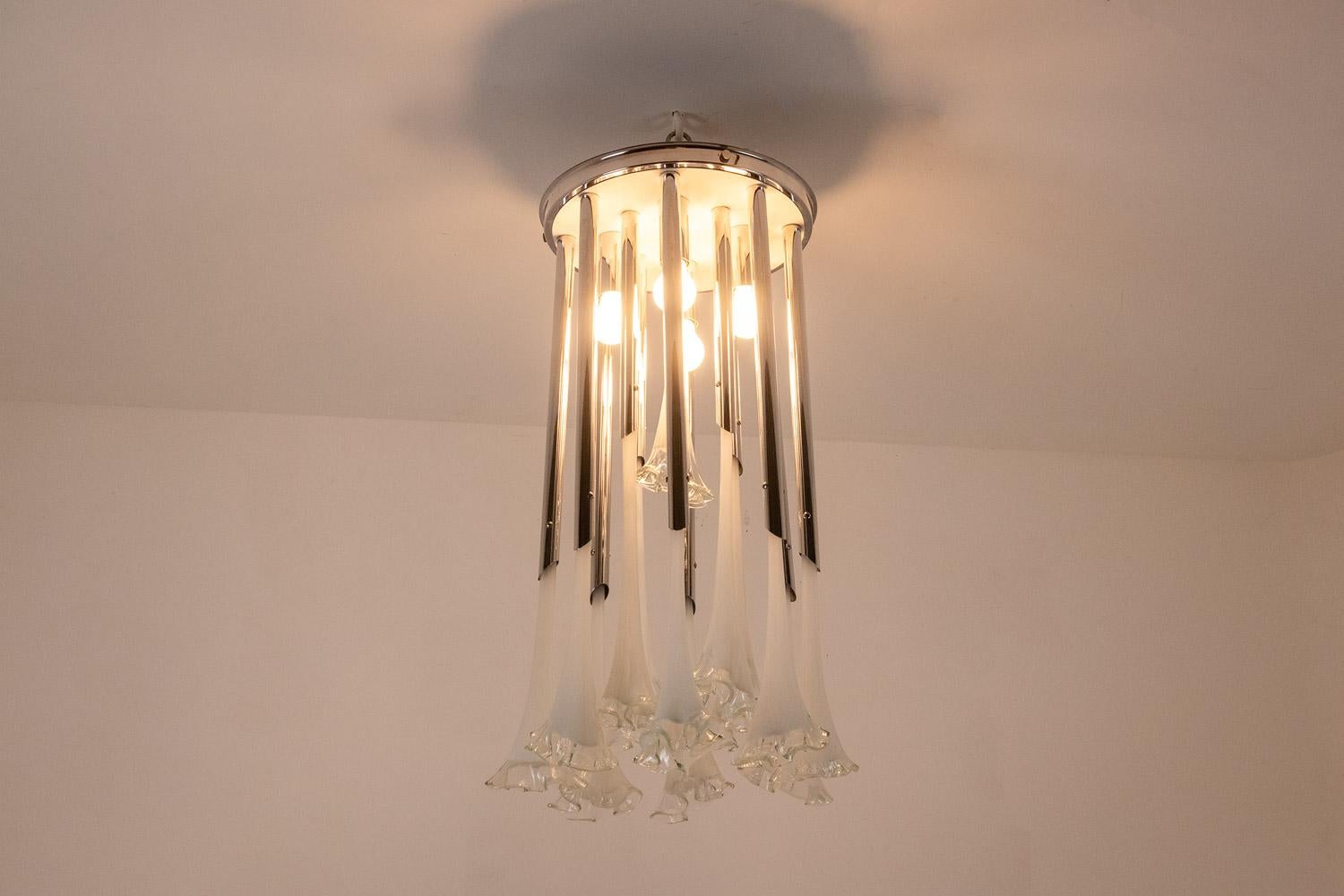 Lampadario in vetro di Murano con tubi decorati a fiori inseriti in una struttura circolare in metallo cromato.

Opera italiana realizzata negli anni '1970.

Dimensioni: H. H. 40 x D. 40 cm

Elettricità nuova e funzionale. Funziona con 4 lampadine