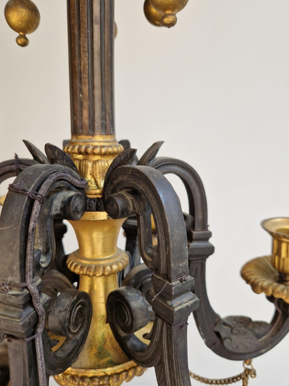 Très beau lustre à 6 appliques en bronze patiné et doré, décoré de feuillages stylisés, de sphères suspendues, de pommes de pin. Vers 1840. En très bon état, notre lustre a été percé pour l'électricité. Ce modèle charmant et très élégant est