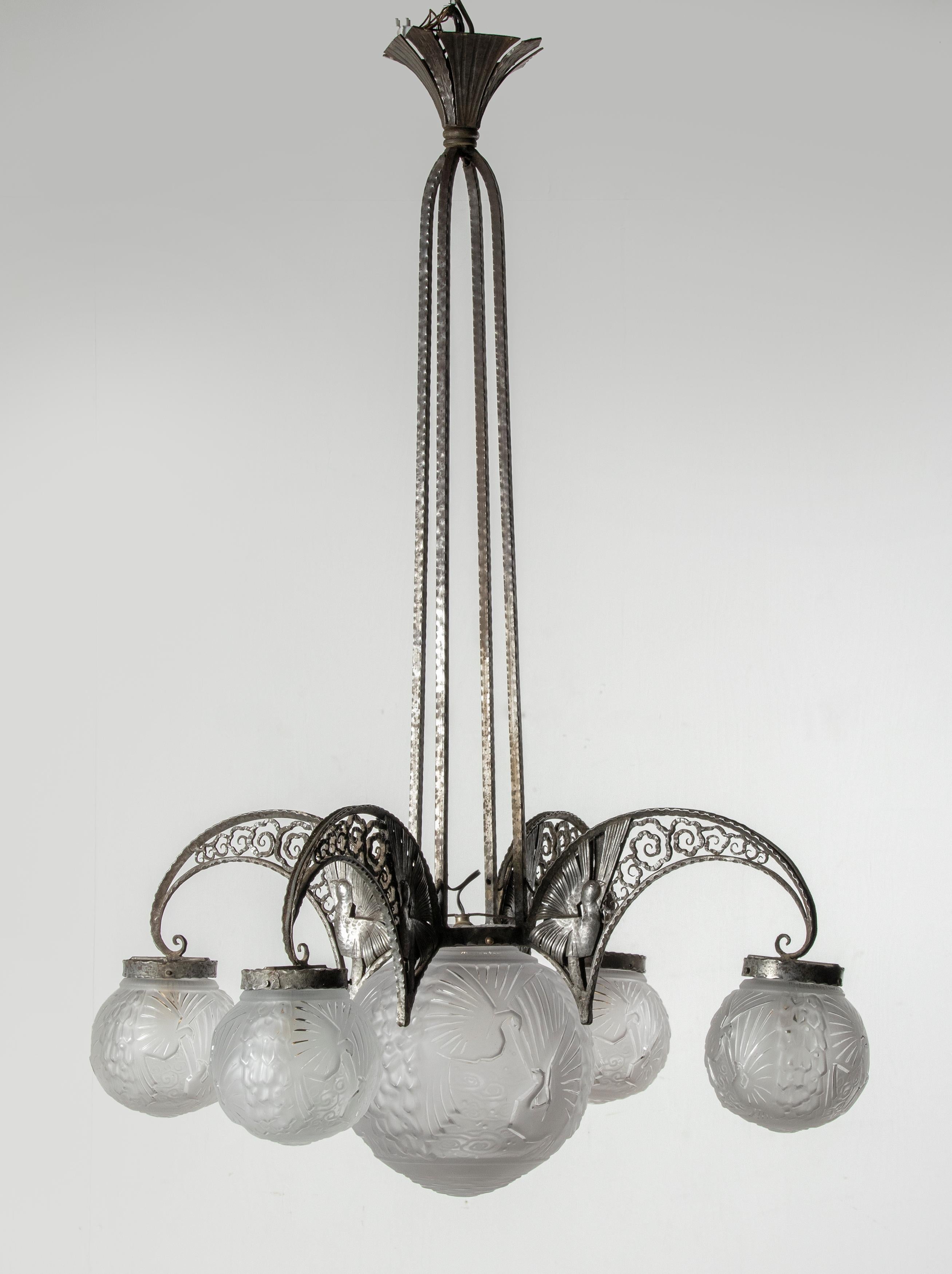 Ein großer und schön gestalteter Kronleuchter aus der französischen Art Déco-Periode. Die Lampe ist sehr raffiniert aus Schmiedeeisen gefertigt. Die Lampe ist auf beiden Seiten an jedem Arm mit Pfauen verziert. Er hat 5 Lichter mit dem originalen