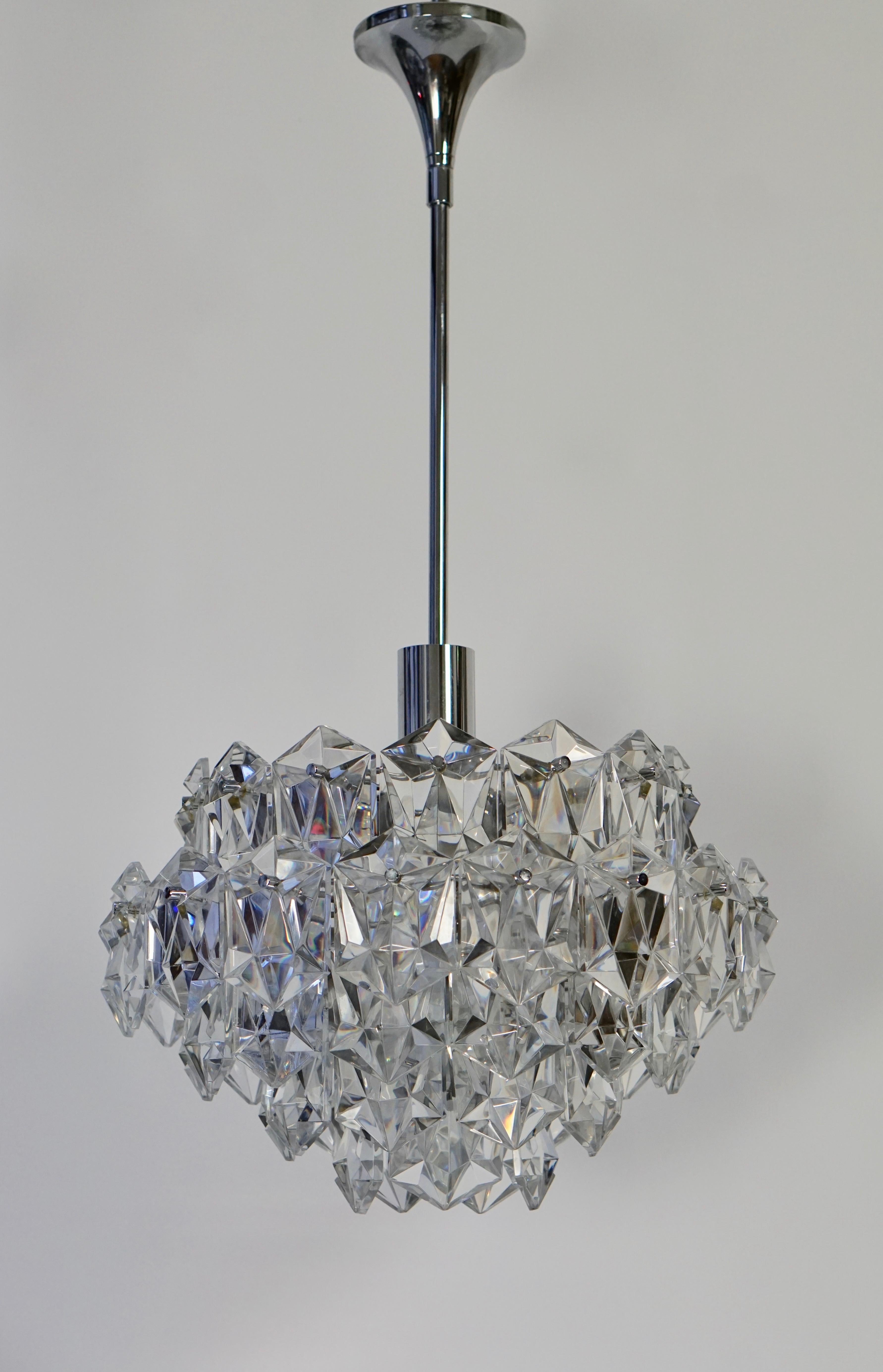 This chandelier has a very unique design, as it is made out of cut crystal glasses, with a unconventional shape whereas the chandelier has a Classic shape itself. The body of the chandelier is held up by a tubular metal pole, which can be connected