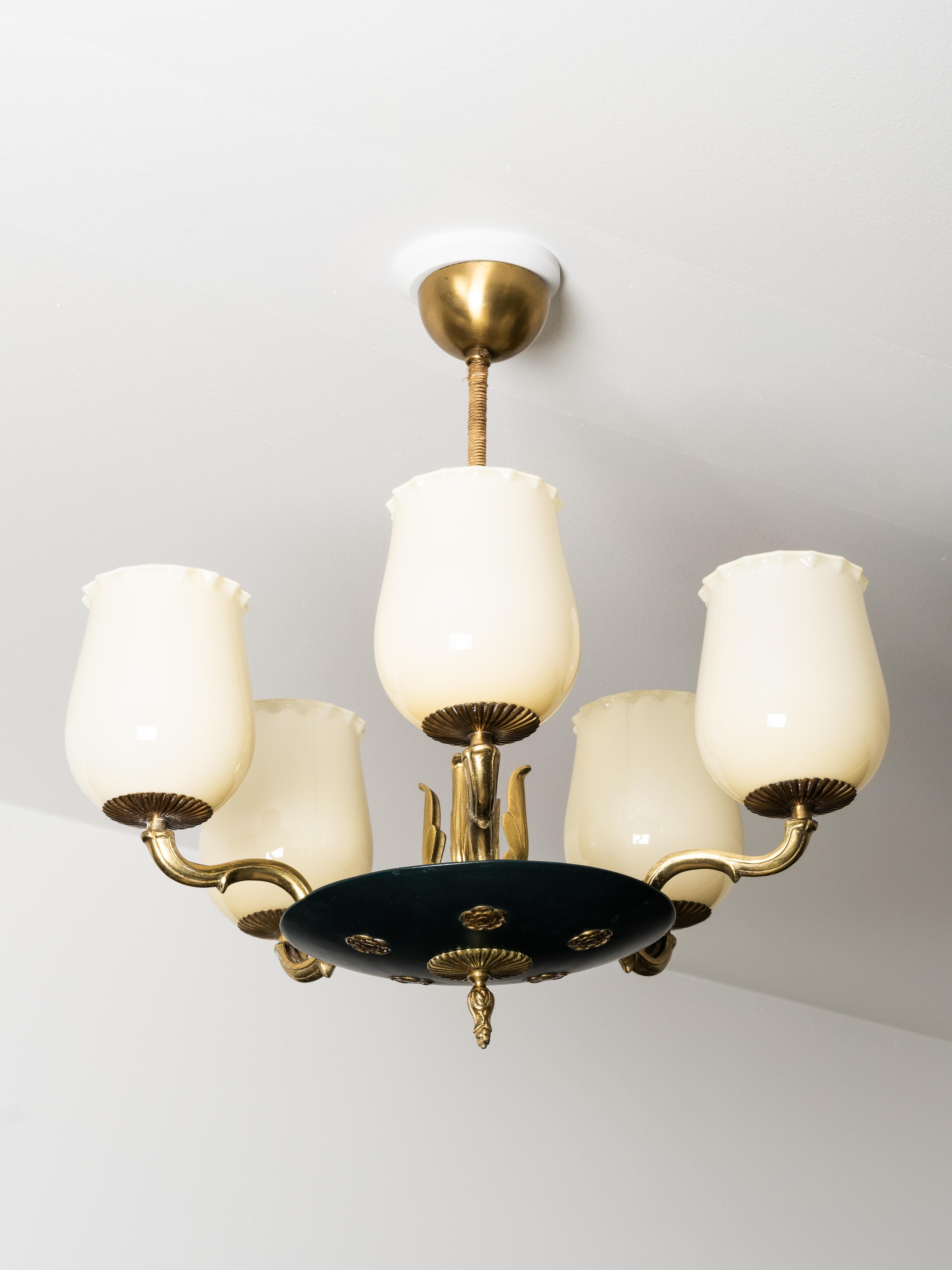 Un raro lampadario giovanile di Paavo Tynell, prodotto da Taito Oy negli anni '30 come Model 1374/5. Questo design a cinque bracci combina ottone, metallo verniciato e paralumi in vetro opalino, riflettendo il raffinato linguaggio decorativo di