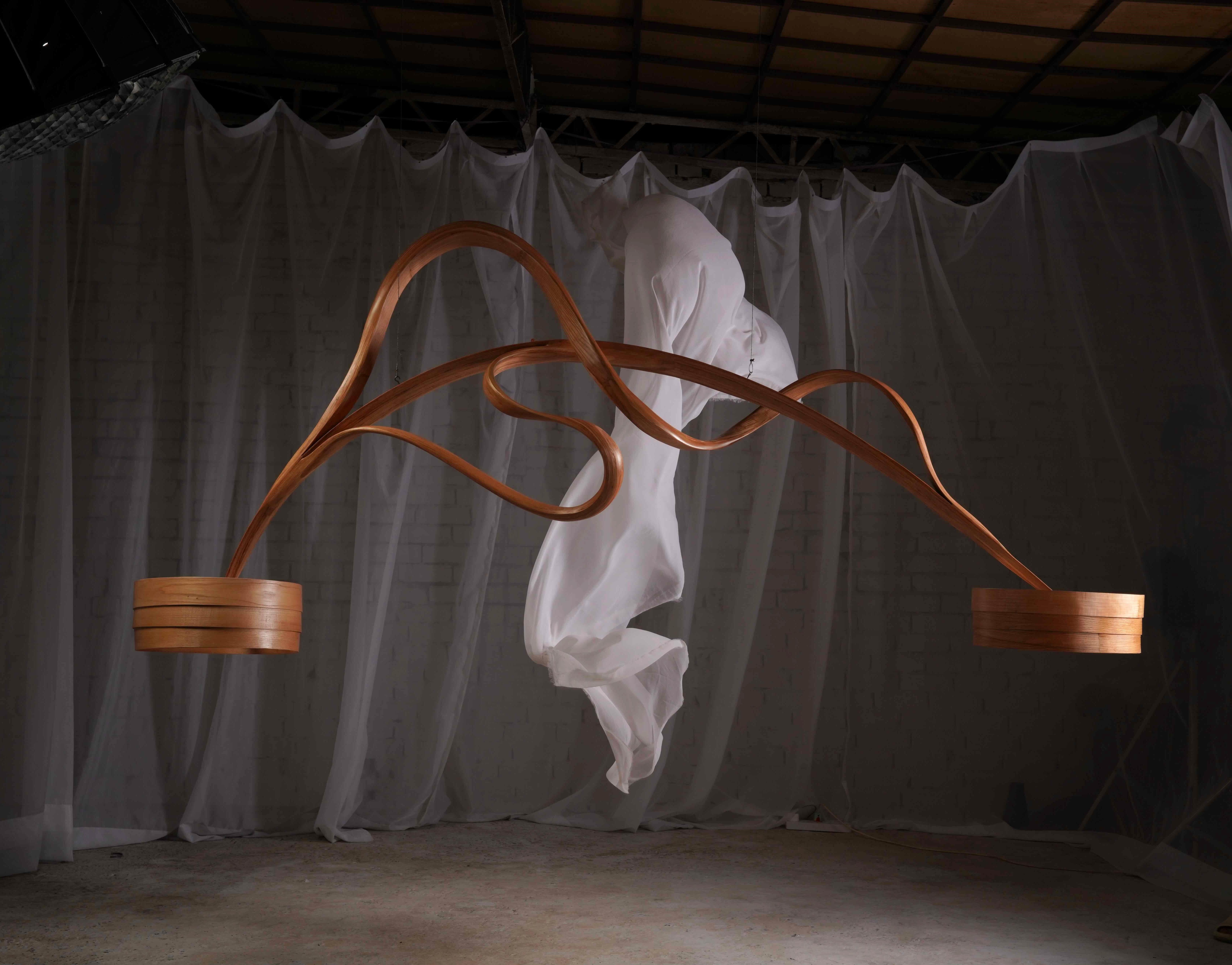 This piece follows a linear form with lighting points at each end - designed for hanging over tables. A minimally designed piece to retain focus on the craftsmanship and on how the wood has been morphed. The silhouette of the piece has been inspired