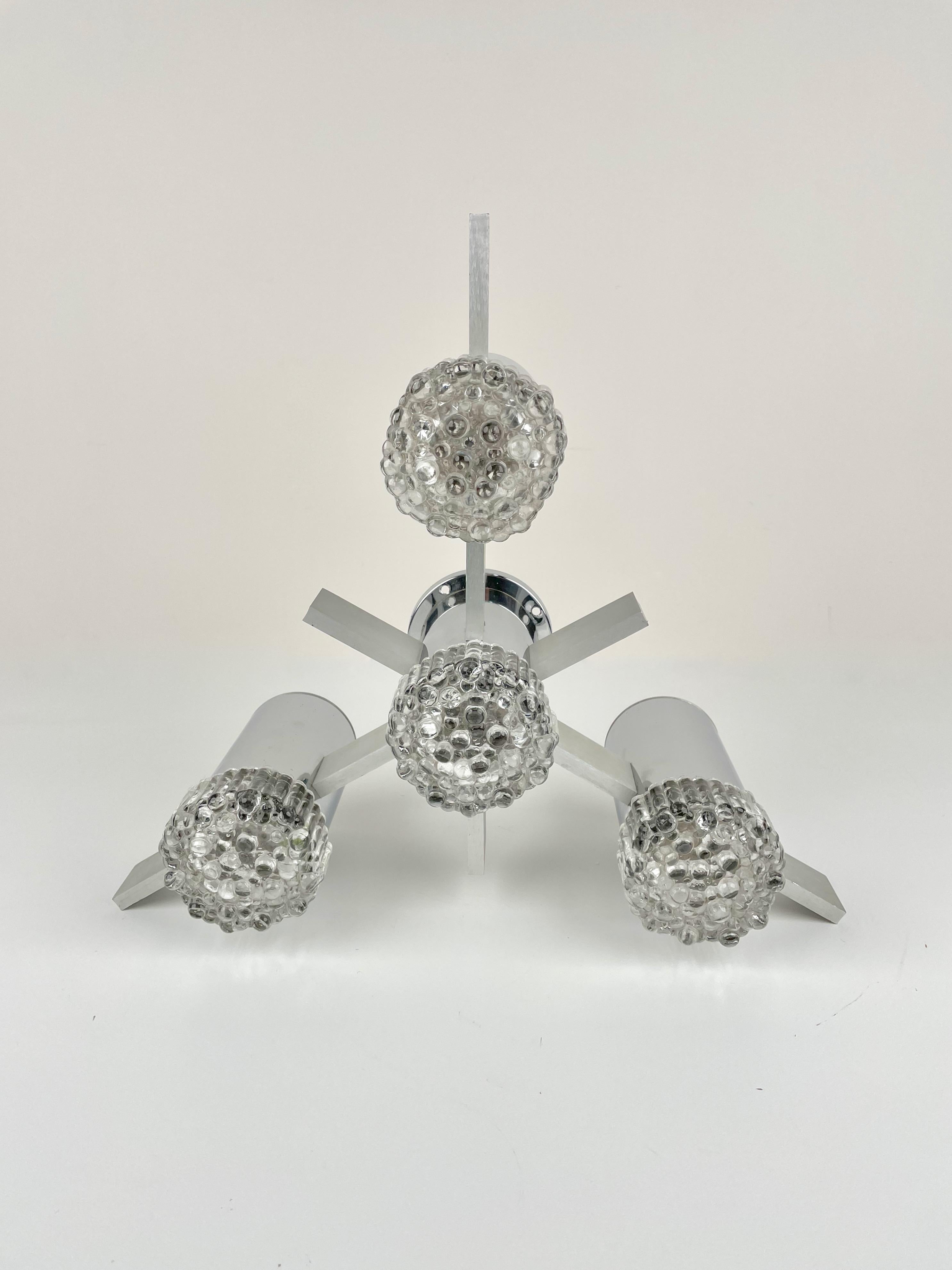 Abstract 1970s chandelier or sconces designed by Gaetano Sciolari for his Italian family's noted lighting company of the same last name. Polished chrome metal tubes house each bulb and are capped by a molded geometric pattern glass cover. Brushed