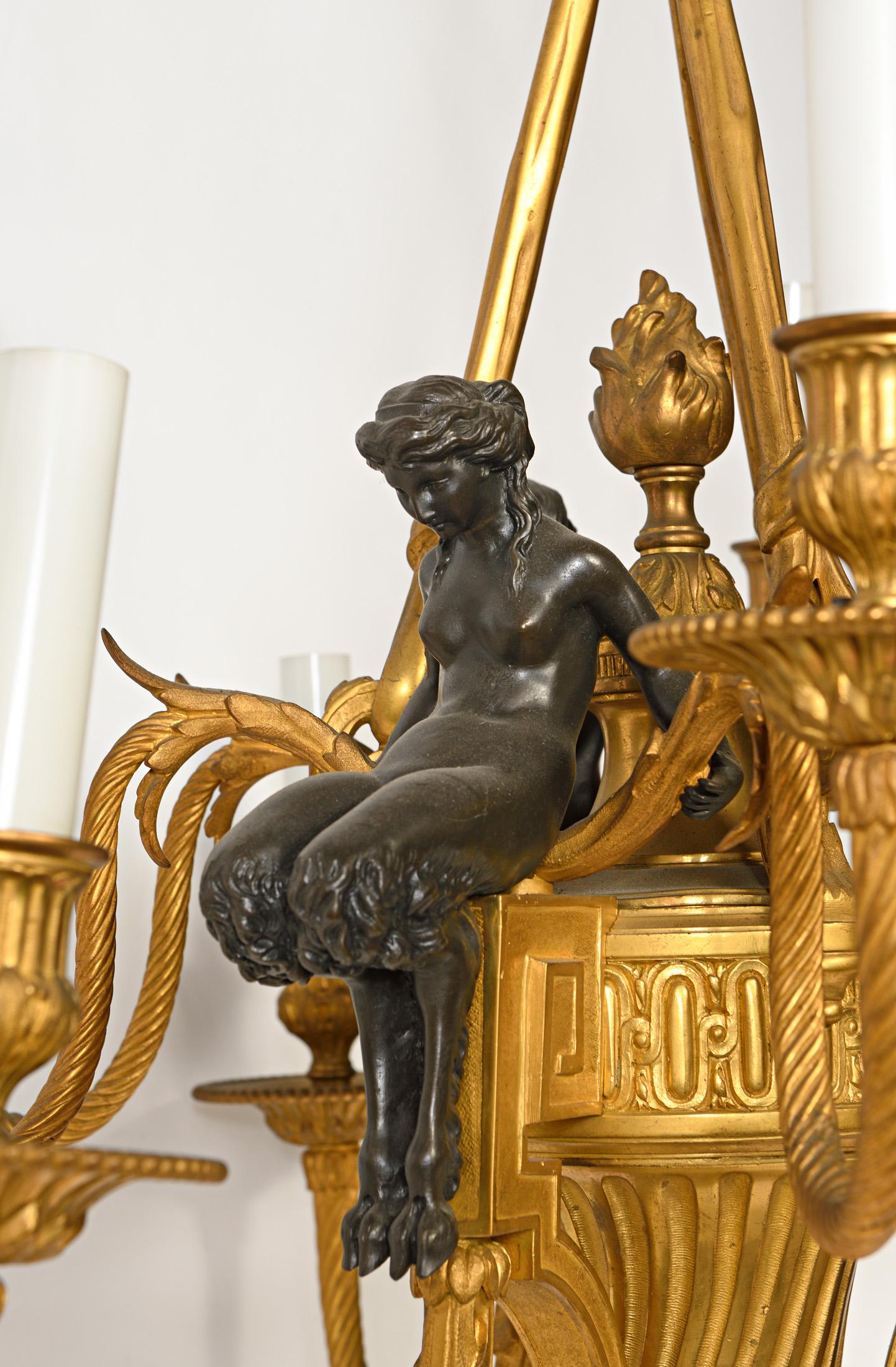 Magnifique lampe à 9 lumières en bronze doré de style Louis XVI, ornée de figures de dames néoclassiques. Ce magnifique lustre en bronze doré a été merveilleusement coulé et ciselé à la main avec du bronze doré bicolore. Chaque belle dame est
