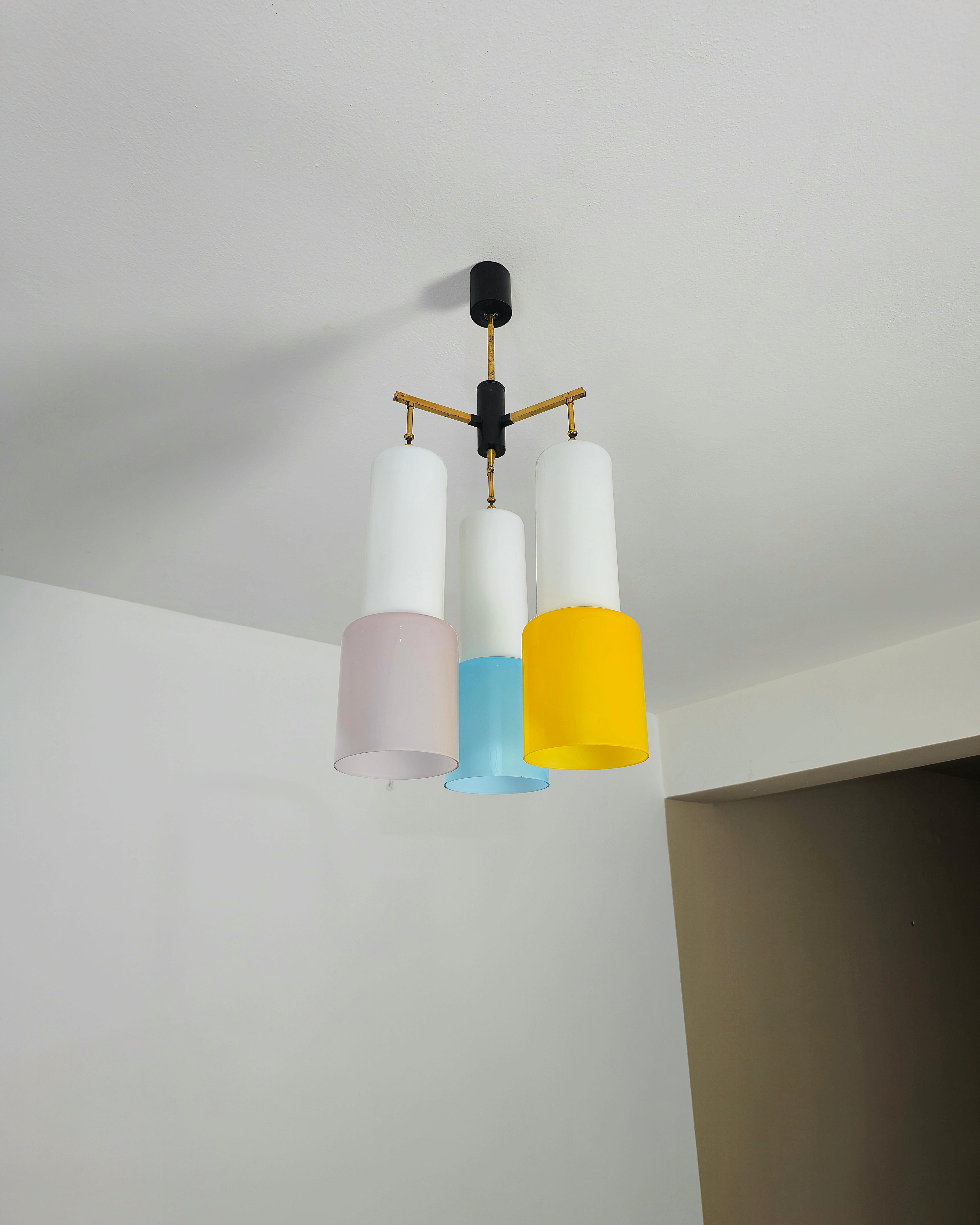 Simpatic 3 lights E27 chandelier attributed to Stilnovo, made with brass structure. Each cylindrical diffuser is in white milky glass with additional milky glass superimposed in shades of wisteria, yellow and light blue. Made in Italy in the