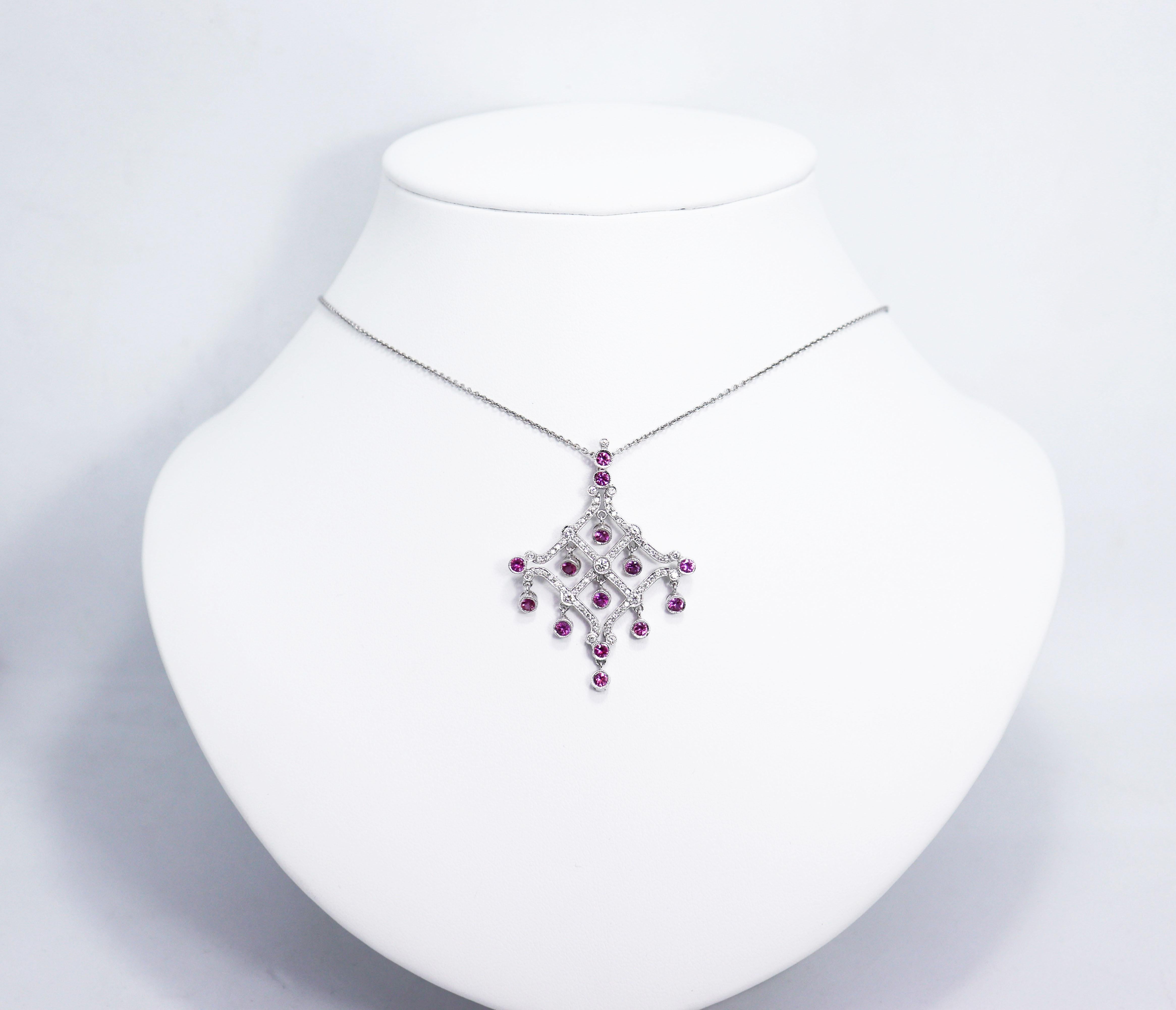 This unique chandelier pendant is beautifully set with 65 round brilliant cut diamonds weighing a total approximate weight of 0.55ct all rubover and grain set in a diamond shaped mount. The pendant is adorned with a cascade of 14 pink sapphires
