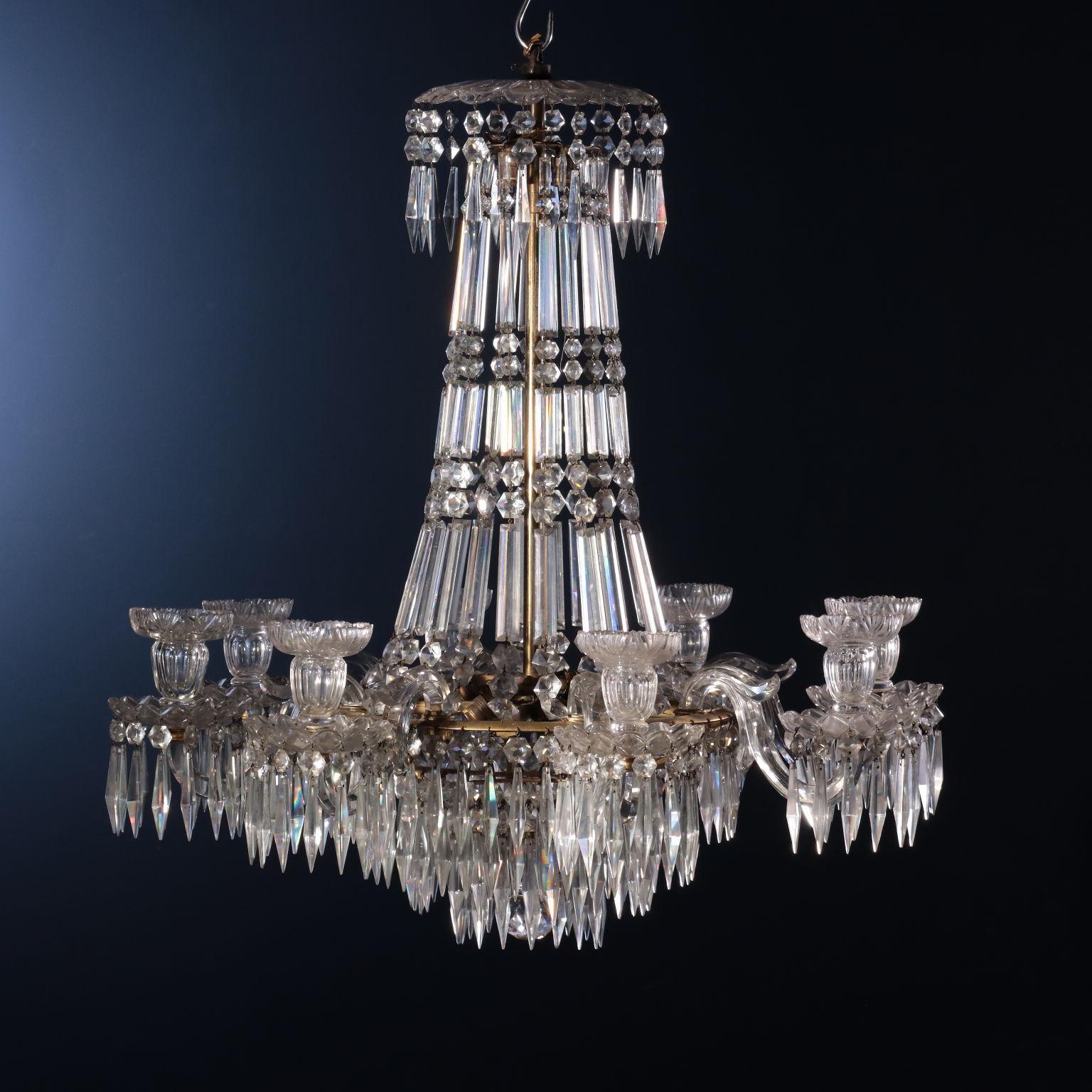 8-arm chandelier in cut crystal with candle holders. The arms are grafted onto a support structure in gilded brass with multiple levels in which there are the lodgings for the glasses of the arms. The brass structure supports a cascade of cut