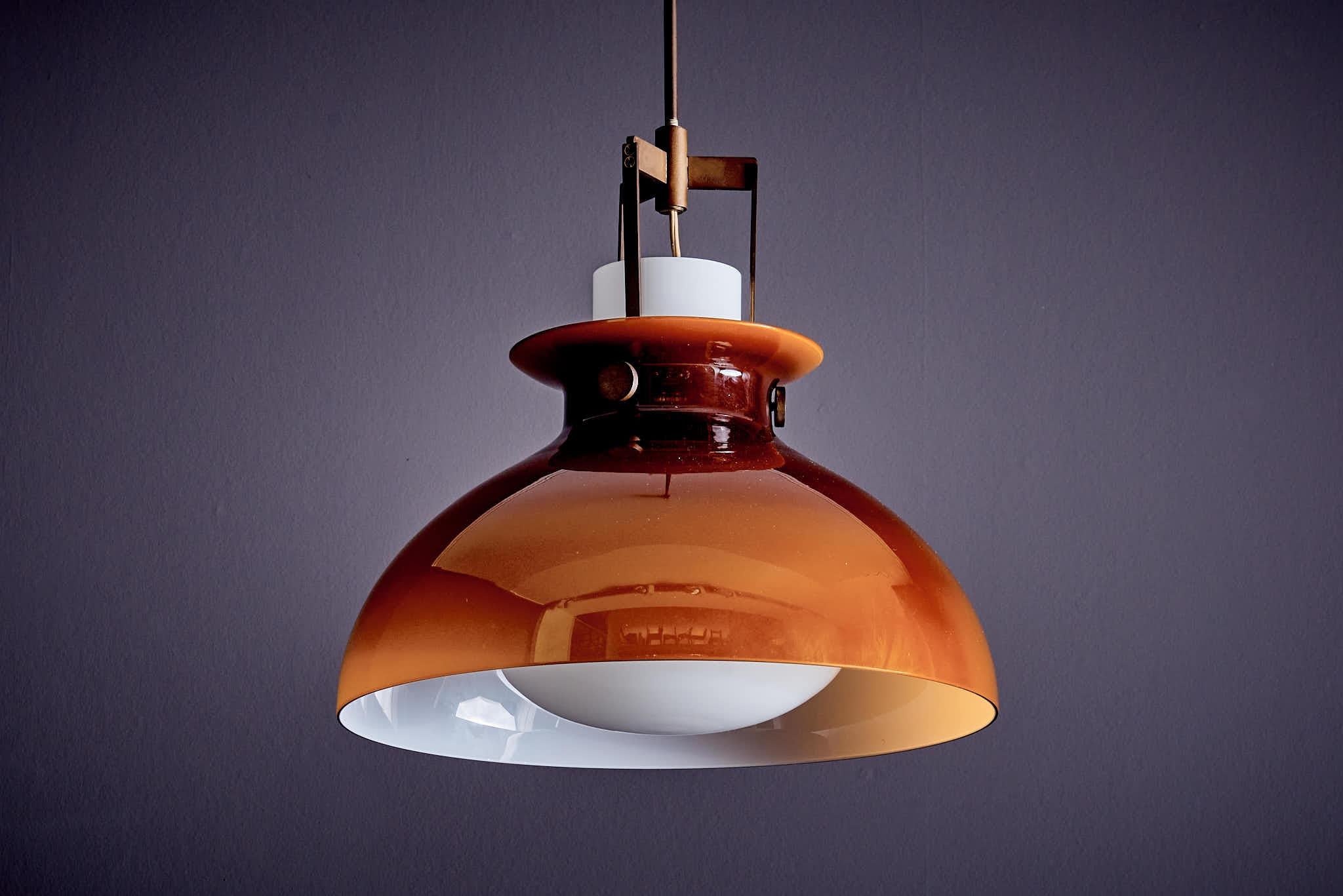 Innovativa lampada a sospensione con due diffusori in vetro e una struttura metallica realizzata nel 1960 da Paolo Caliari per Paolo Venini. L'altezza totale della lampada a sospensione, compresi il diffusore in vetro e la sospensione in ottone, è