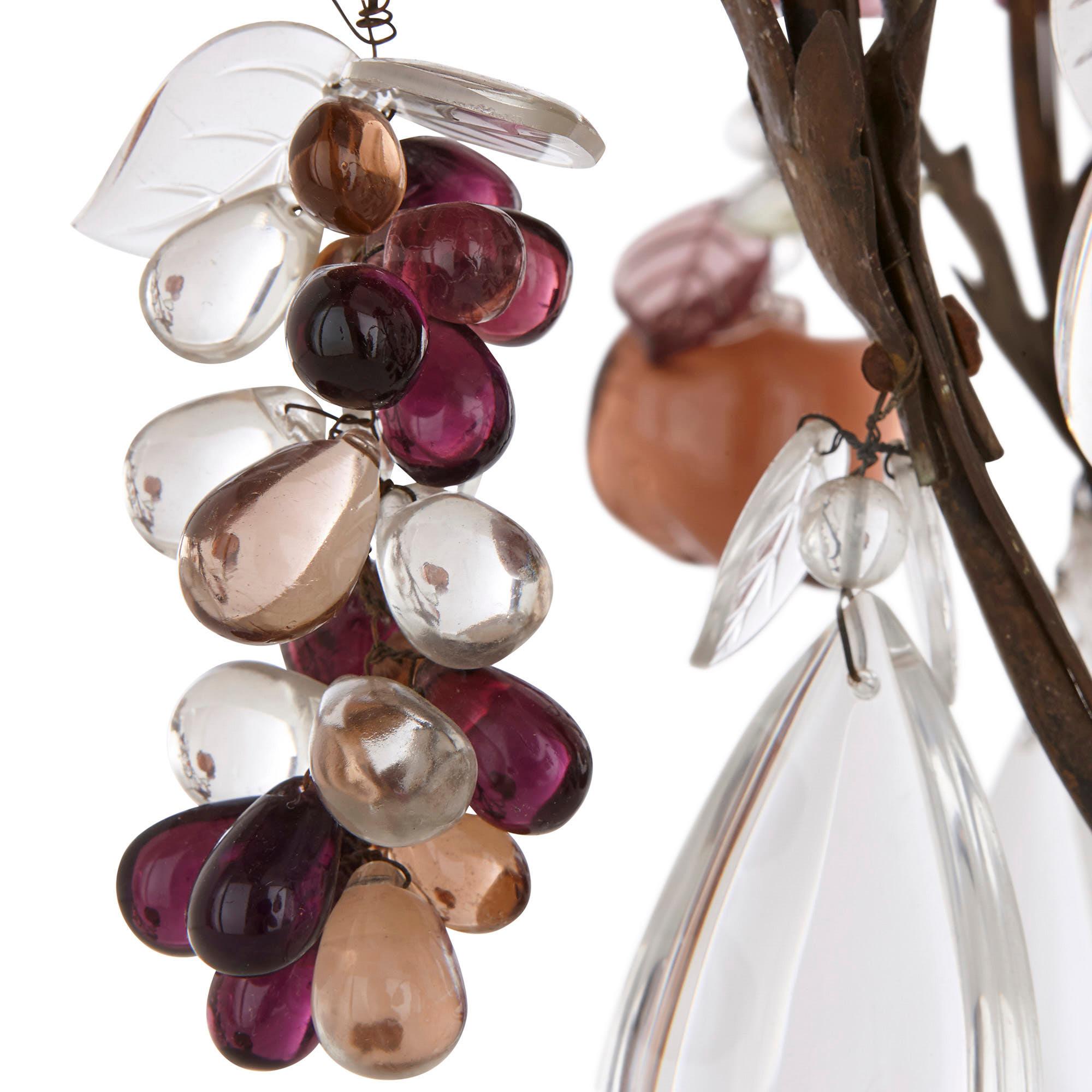 This chandelier is unique for its fruit-shaped glass, rock crystal and quartz pendants. These pink, purple, white and orange pears, apples, and grapes adorn the chandelier’s foliate metal frame. 

The chandelier features a top canopy with several