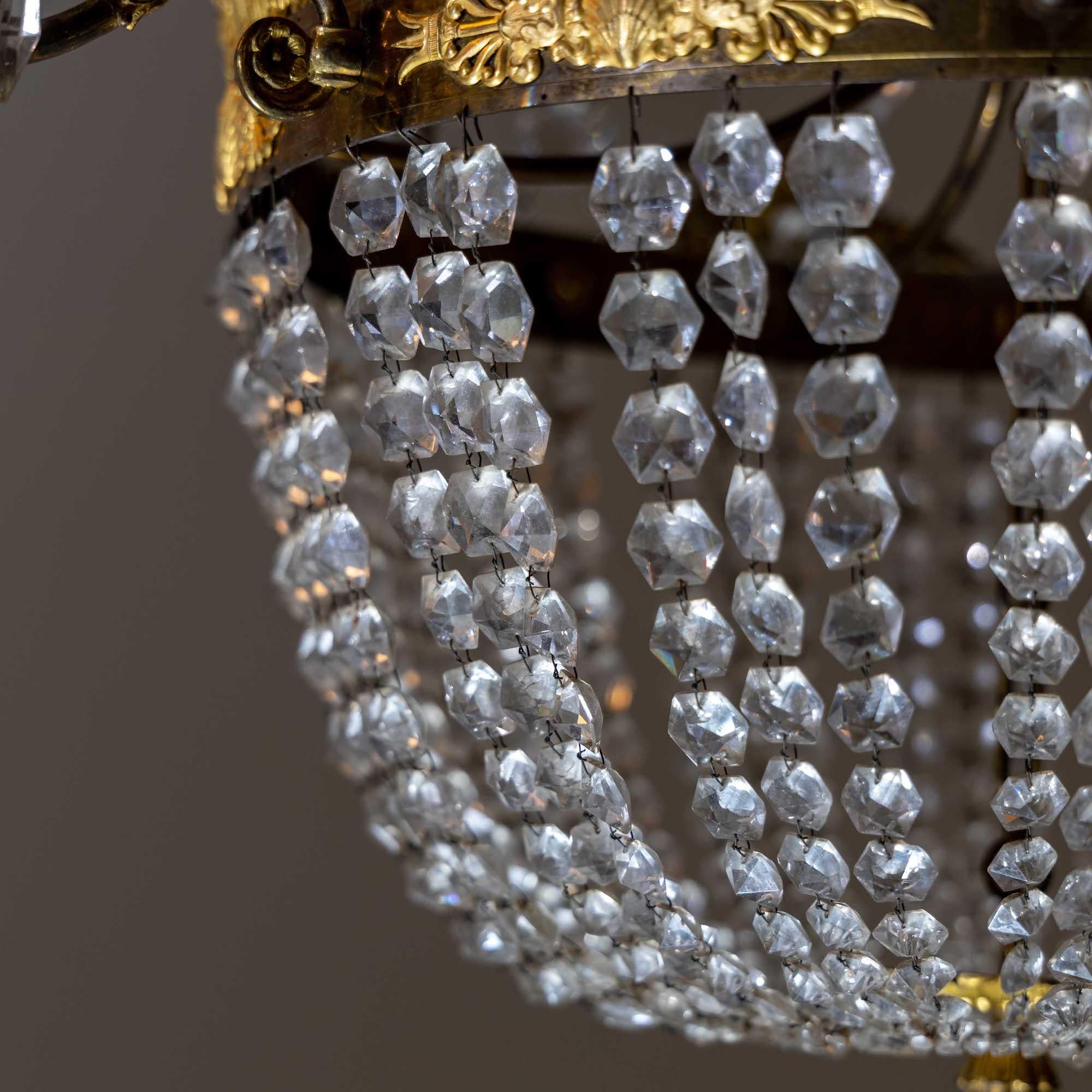 Four-light ceiling chandelier with crystal hangings and fire-gilded acanthus leaf decorations.