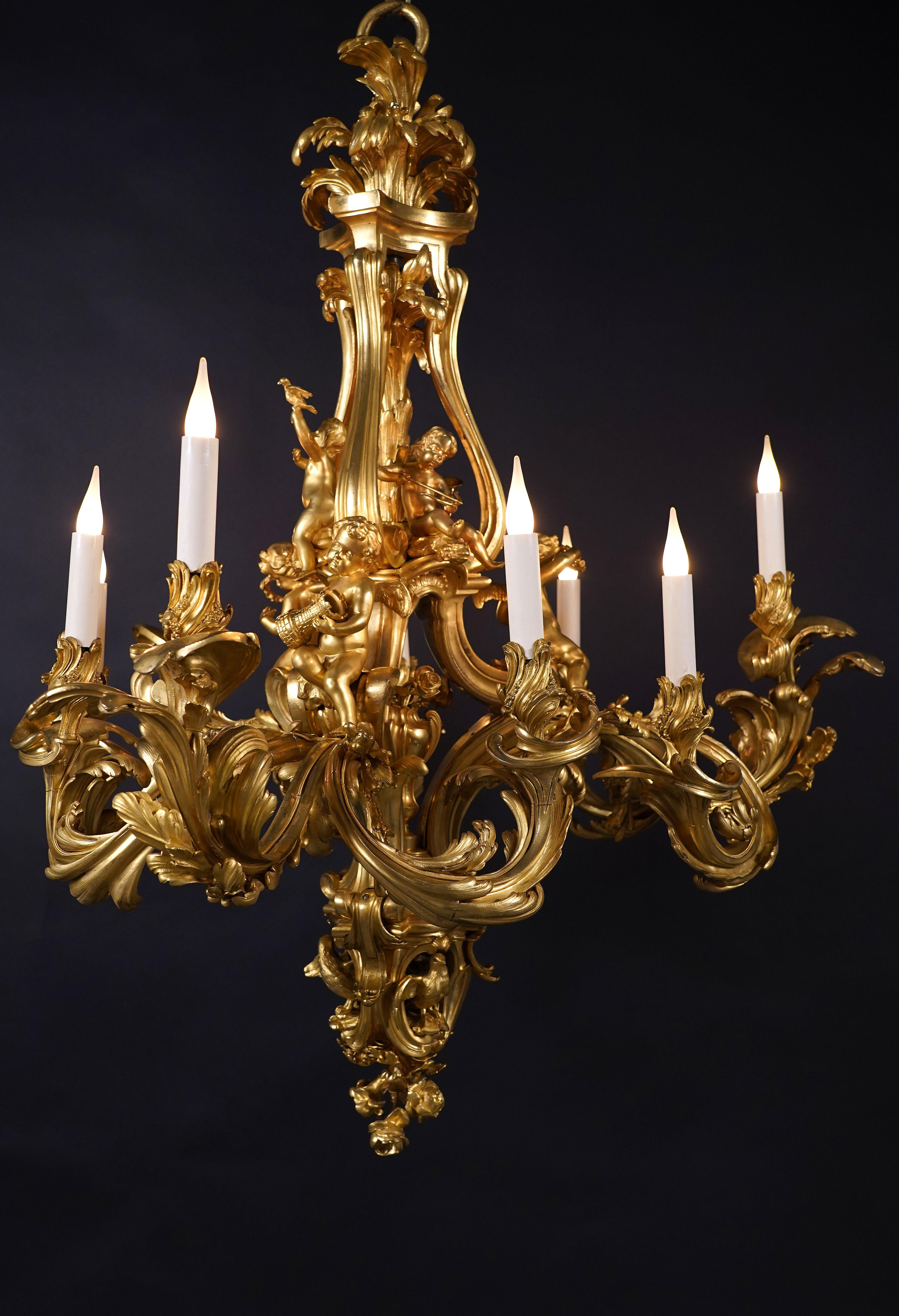Beautiful Louis XV style chased gilt bronze chandelier with nine lights. The central part of the chandelier is formed by three scrolls and is embellished with a flowering vase and cupids.
Two of them hold laurel wreaths, another a tower in reference