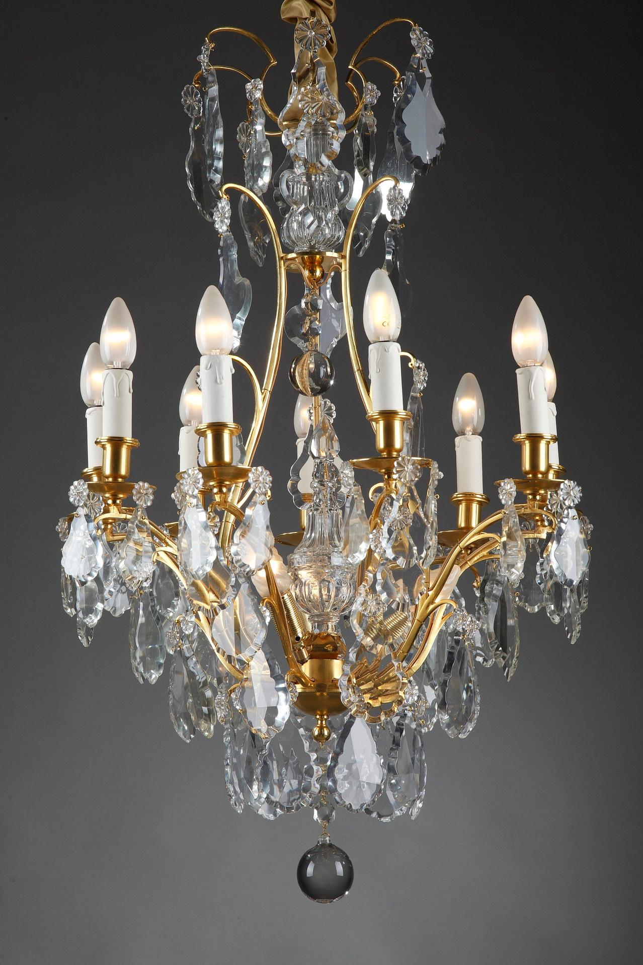 Large chandelier with cut crystal pendants in the Louis XV style. The gilded bronze frame is composed of eight curved arms of lights and numerous crystals finished by rosettes. The central axis is decorated with a dagger on the upper and lower part