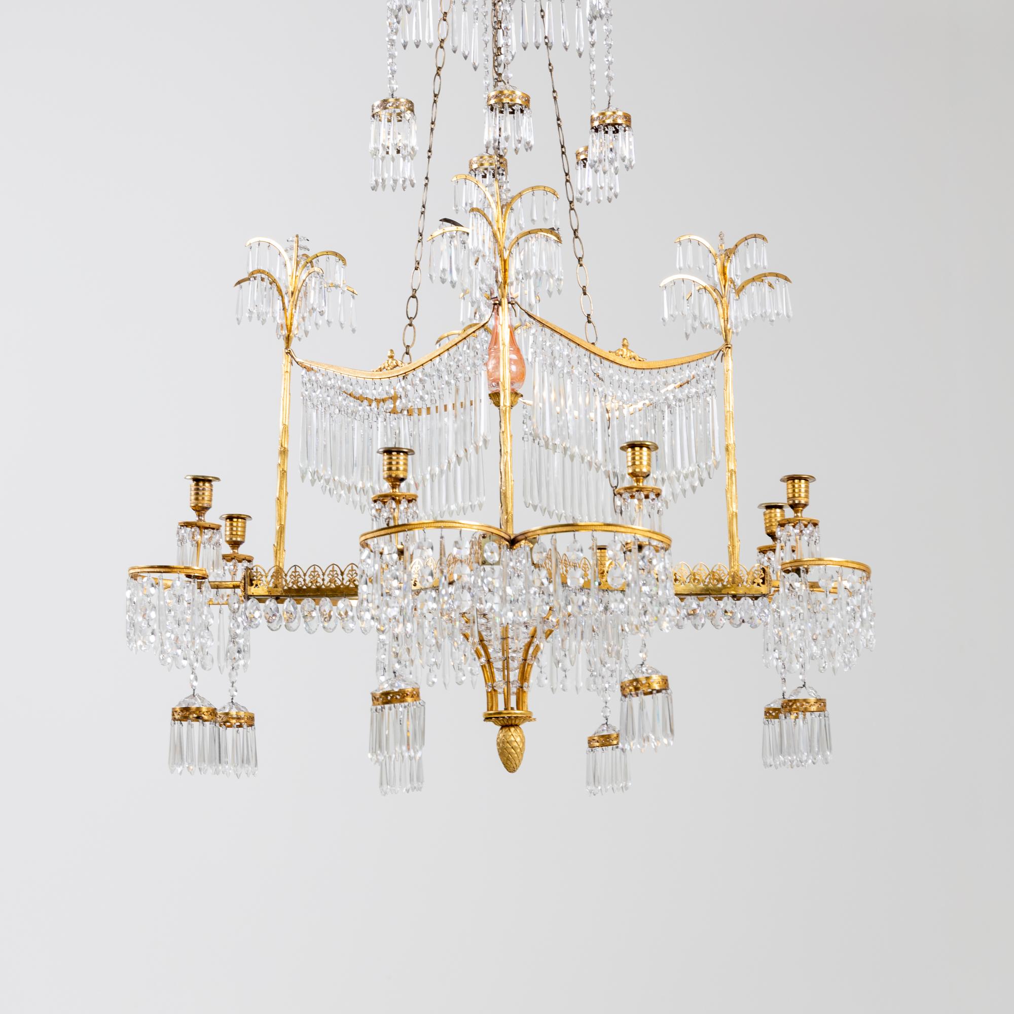 Important neoclassical chandelier by Werner & Mieth Berlin circa 1800-1810.
The chandelier is made of fire-gilt bronze and hangings of cut glass prisms and rose-tinted glass bodies.
The eight-armed chandelier has three tiers. The lower tier with