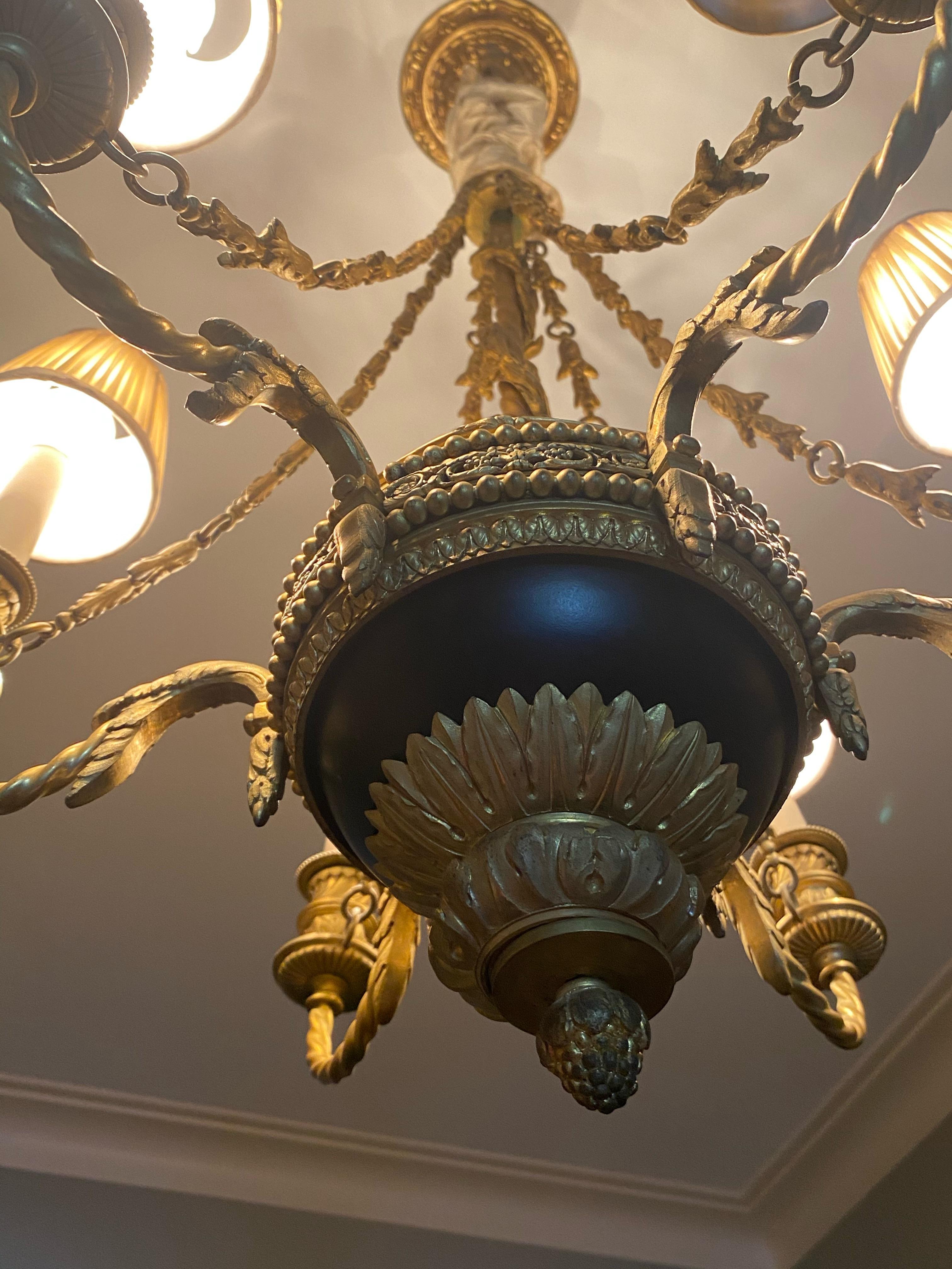 Neo-classical chandelier. The fixture has six attached lamps, each with a matching lamp shade. Fully functioning.