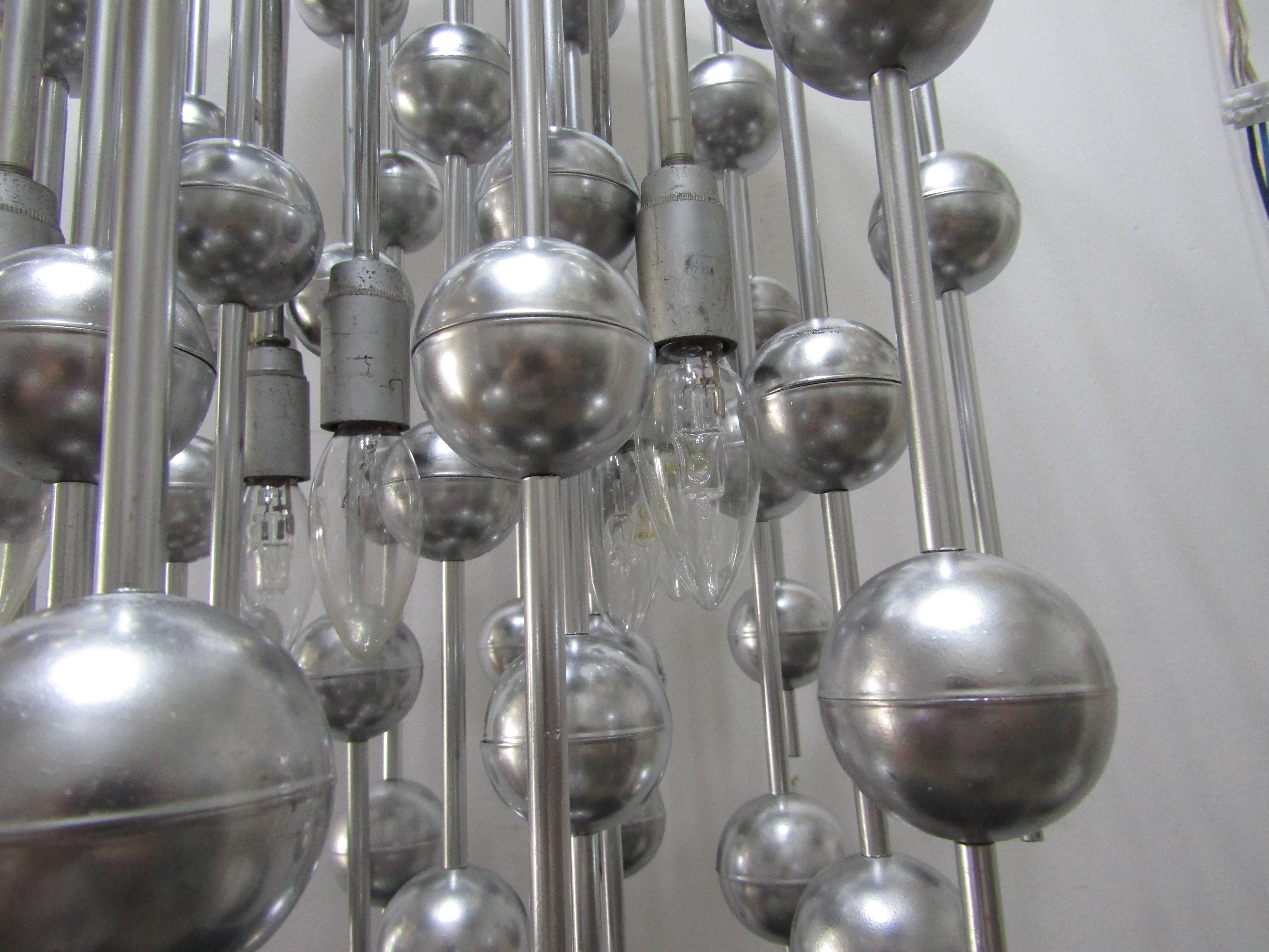 This Ball chandelier was designed by Verner Panton for Swiss manufacturer Lüber in the 1970s. The space age pendant consists of a series of chromed metal balls suspended from several steel rods with eight bulb sockets (max. 60W).