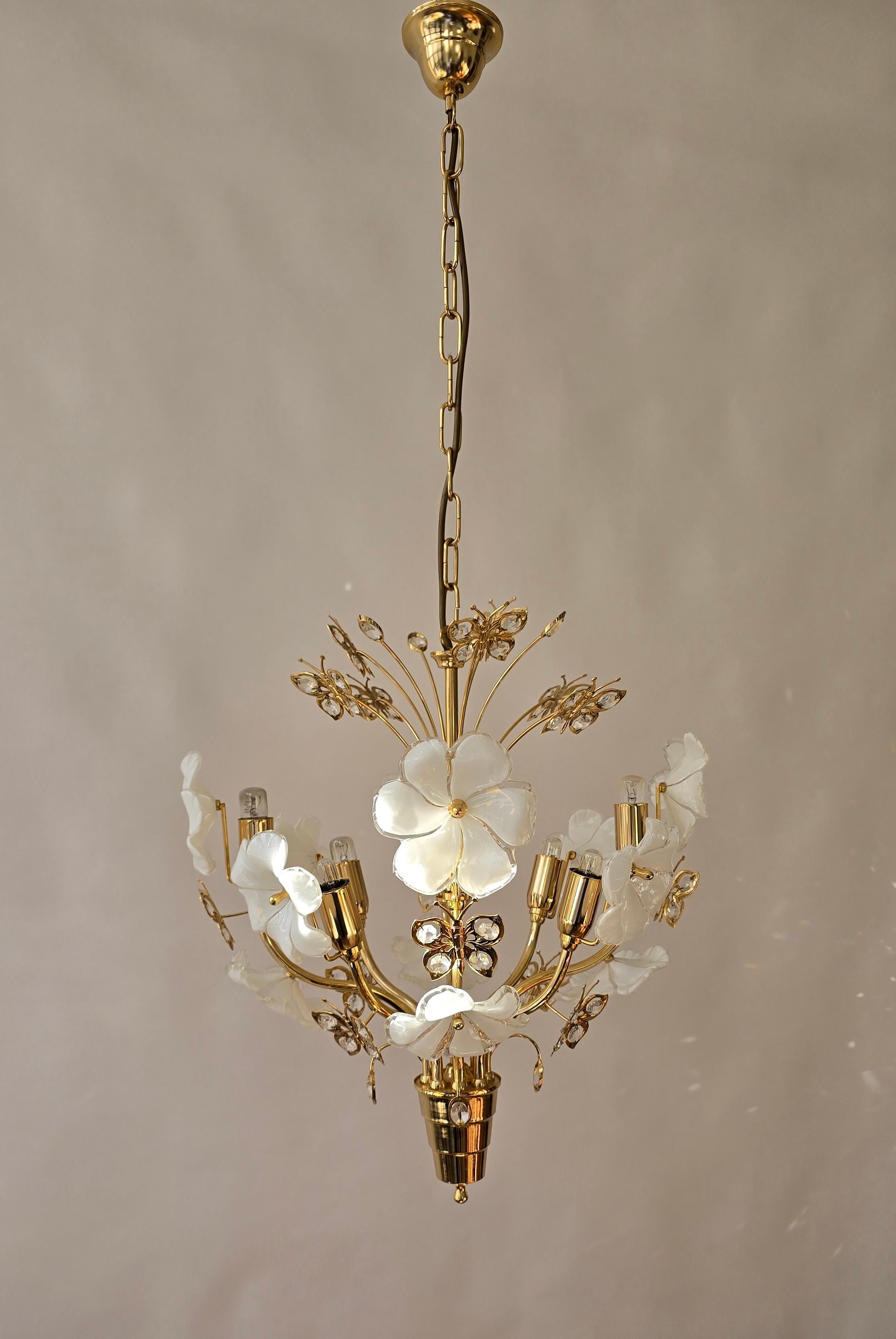 Brass Chandelier with Handmade White Murano Glass Flowers and Crystal Butterflies

The fixture is made of polished brass and richly decorated with hand-blown Murano glass flowers in an elegant opal white hue. Finely cut crystal butterflies and