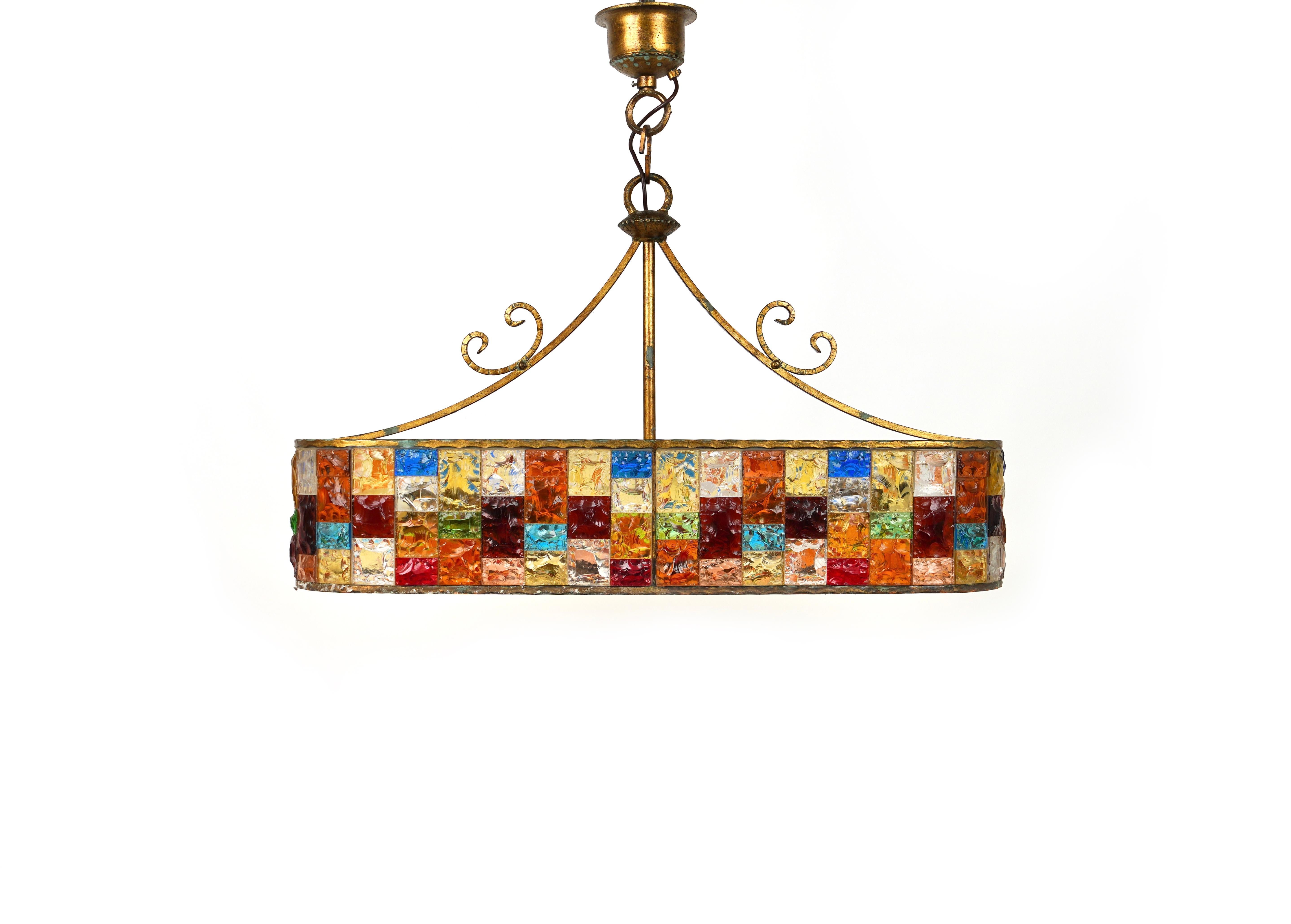 Amazing large Midcentury chandelier in golden wrought iron and multi-color hammered glass produced by Longobard the concurrent of Poliarte at the 1960s / 1970s. 

Made in Italy in the 1970s.

It uses 6 bulbs.
