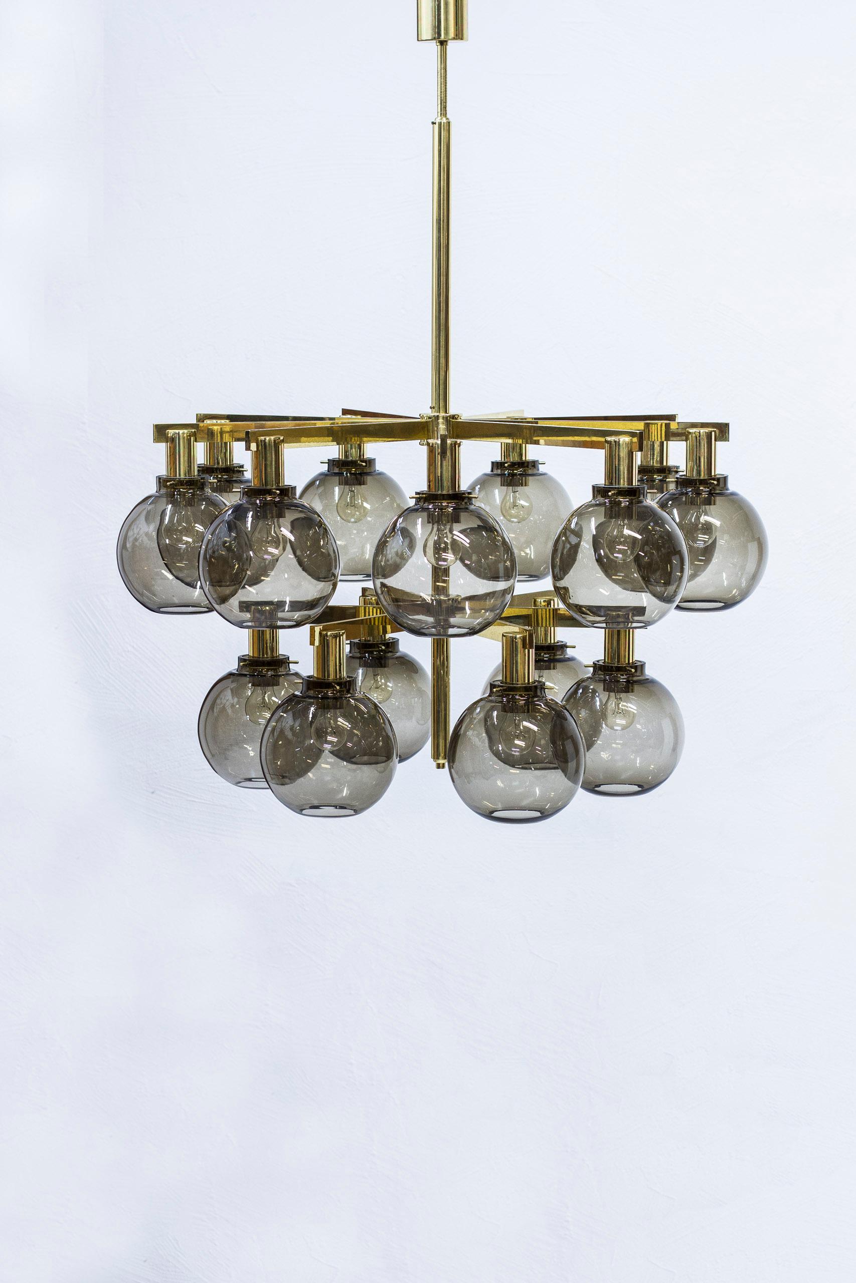 Large chandeliers designed by Hans-Agne Jakobsson during the 1960s. Produced in Sweden by his own company in Markaryd. Fifteen arms of polished brass with smoke colored glass shades. Very good vintage condition with light wear and age related