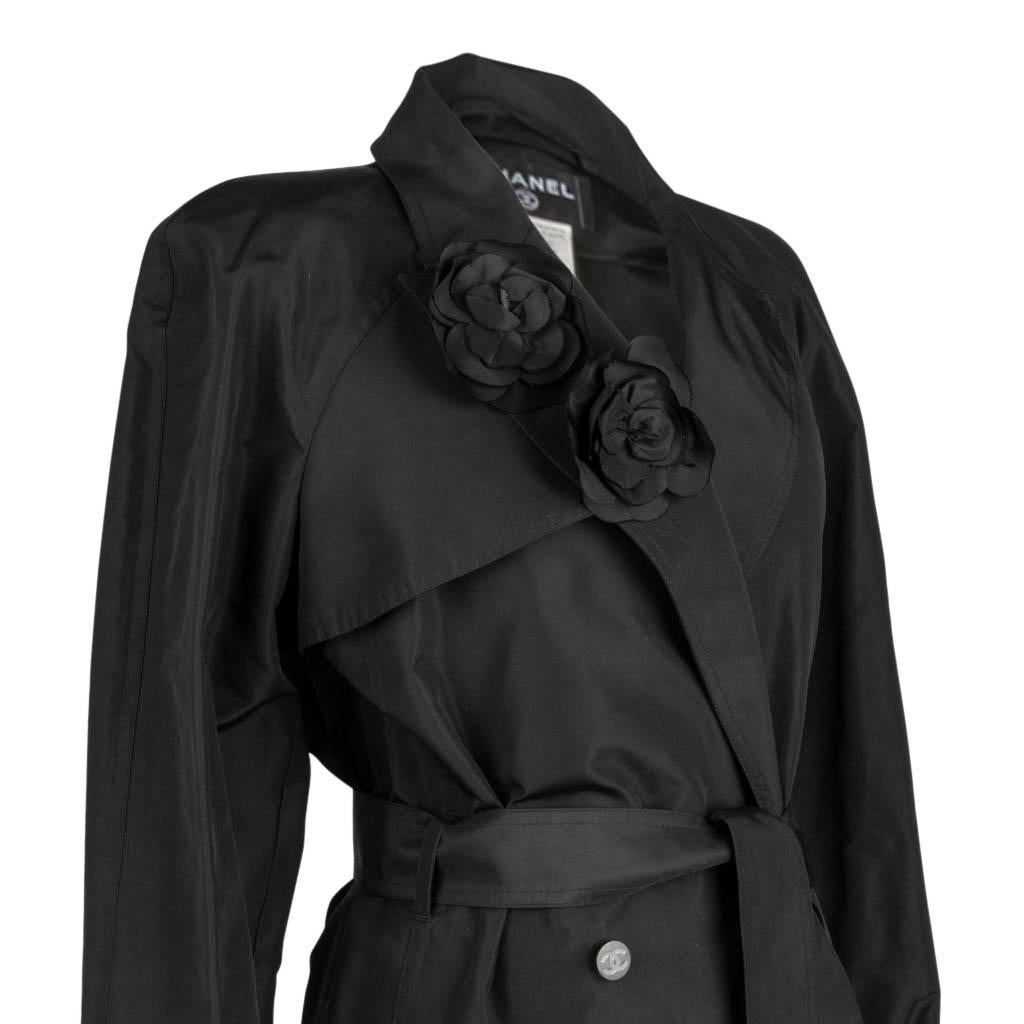 Mightychic offers a Chanel 03C stunning trench style coat.
Jet black 2 on 4 button double breast with a notch lapel.
2 beautiful silk detachable black camellia pins on the right lapel.
Self belt with a square black enamel buckle with CHANEL