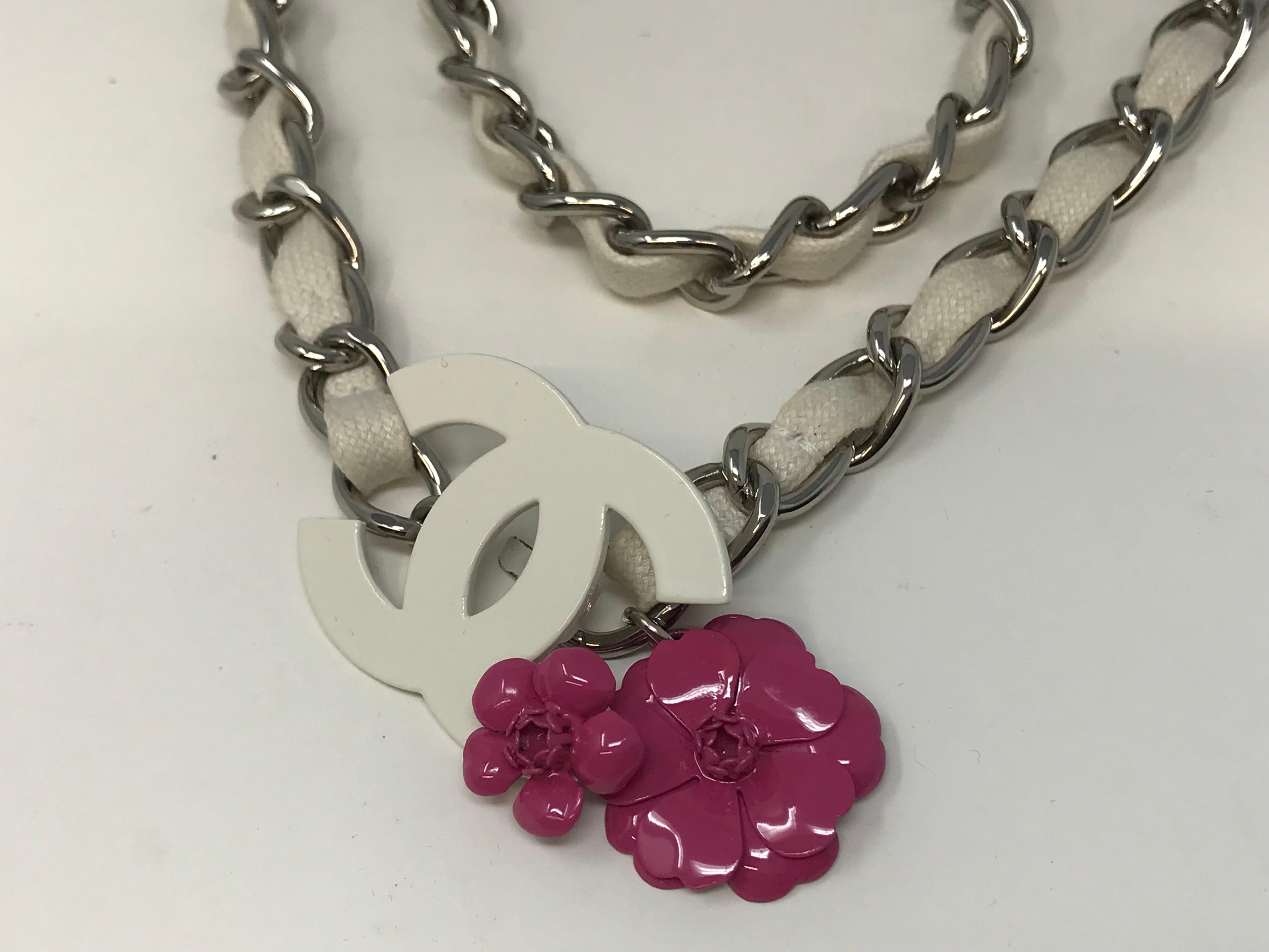 Chanel Chain belt or floral necklace with serial number 04P, made in France with white material and metallic chain. CC monogram and red camellia floral closure, measures 38 inches long. Preowned, but in pristine condition, comes in a box.