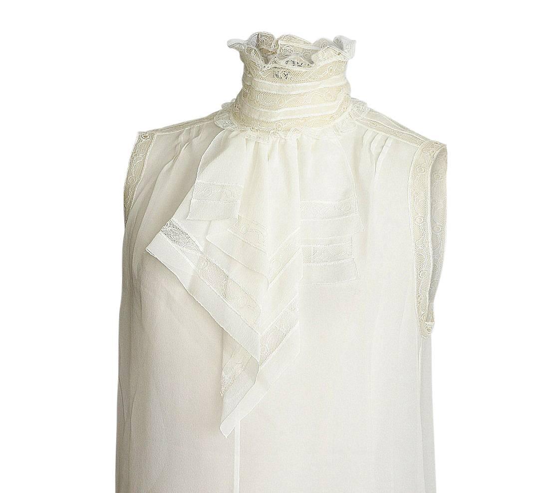 Guaranteed authentic Chanel 07C exquisite winter white silk blouse with lace insets. 
Sleeveless with lace turtle neck and lace inset on shoulders and around arm.
Layered jabot with lace detail. 
Cut up on sides with slightly longer back.
Unique CC