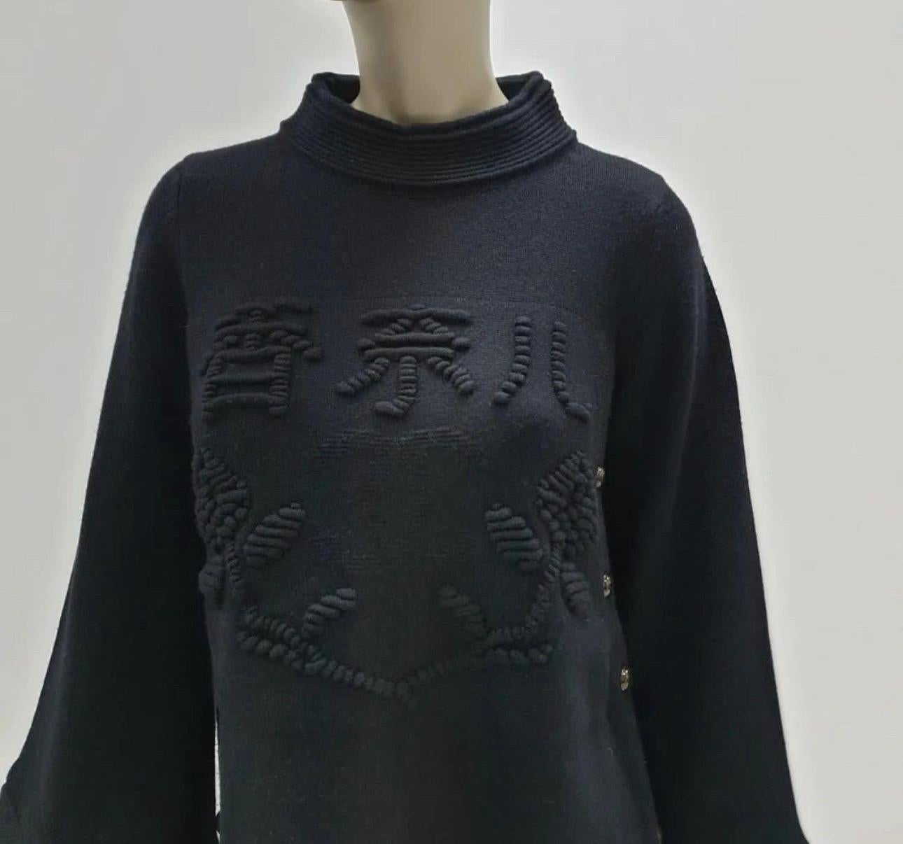 CHANEL black cashmere sweater tunic dress featuring large CC logo, CHANEL in Chinese characters and camellia at center front, bell shape sleeves, CC logo buttons adorn on both sides of dress.

Sz.36

Wool, cashmere and leather parts.

Very good