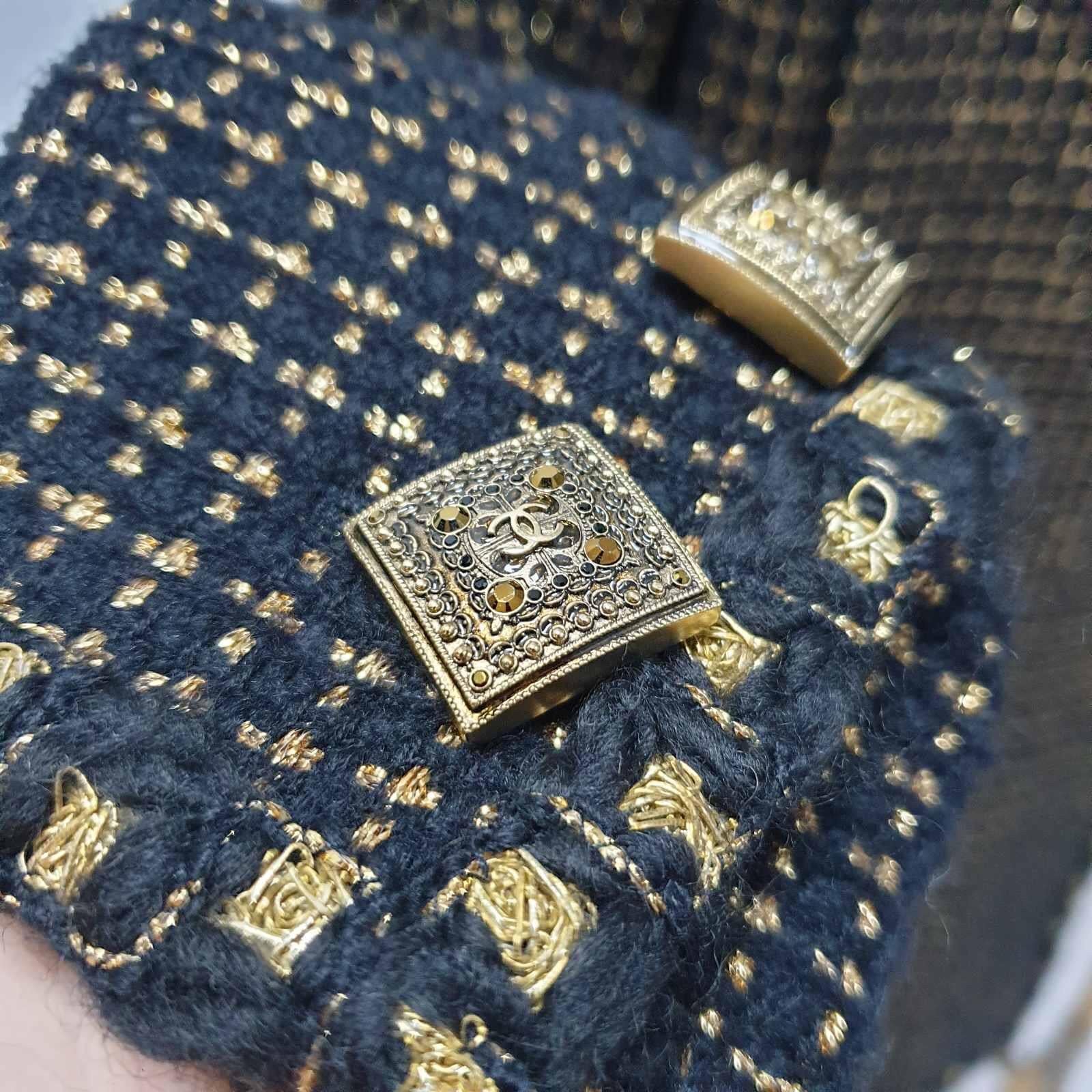 Chanel UNIQUE MOST WANTED LESAGE Black and Metallic Gold Tweed Jacket Coat with Braided Confetti Gold trim, notched collar, two front pockets at waist, 6 Gripoix CC logo at front, sleeves with 10 Gripoix buttons at sleeves (5 each sleeve), 2 Gripoix